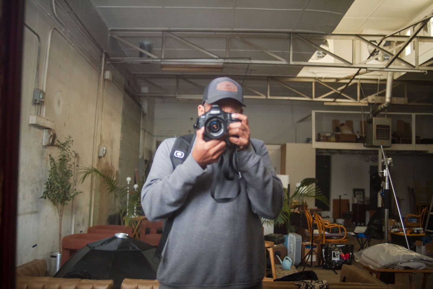 Person in a gray hoodie demonstrates proper camera handling techniques in a workshop setting.