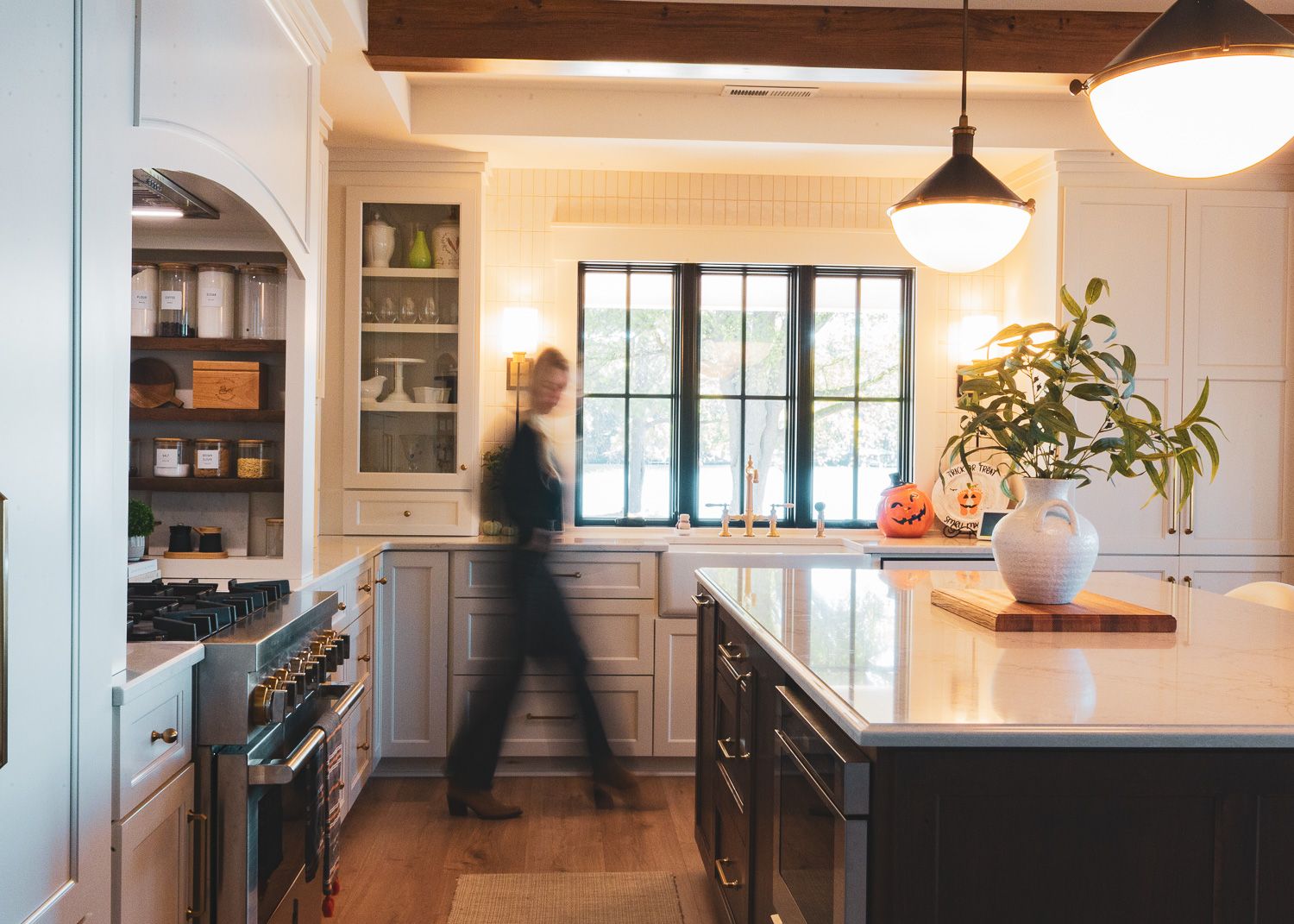 Modern farmhouse style kitchen with white cabinets, wood floors, and pendant lighting in an open concept layout.