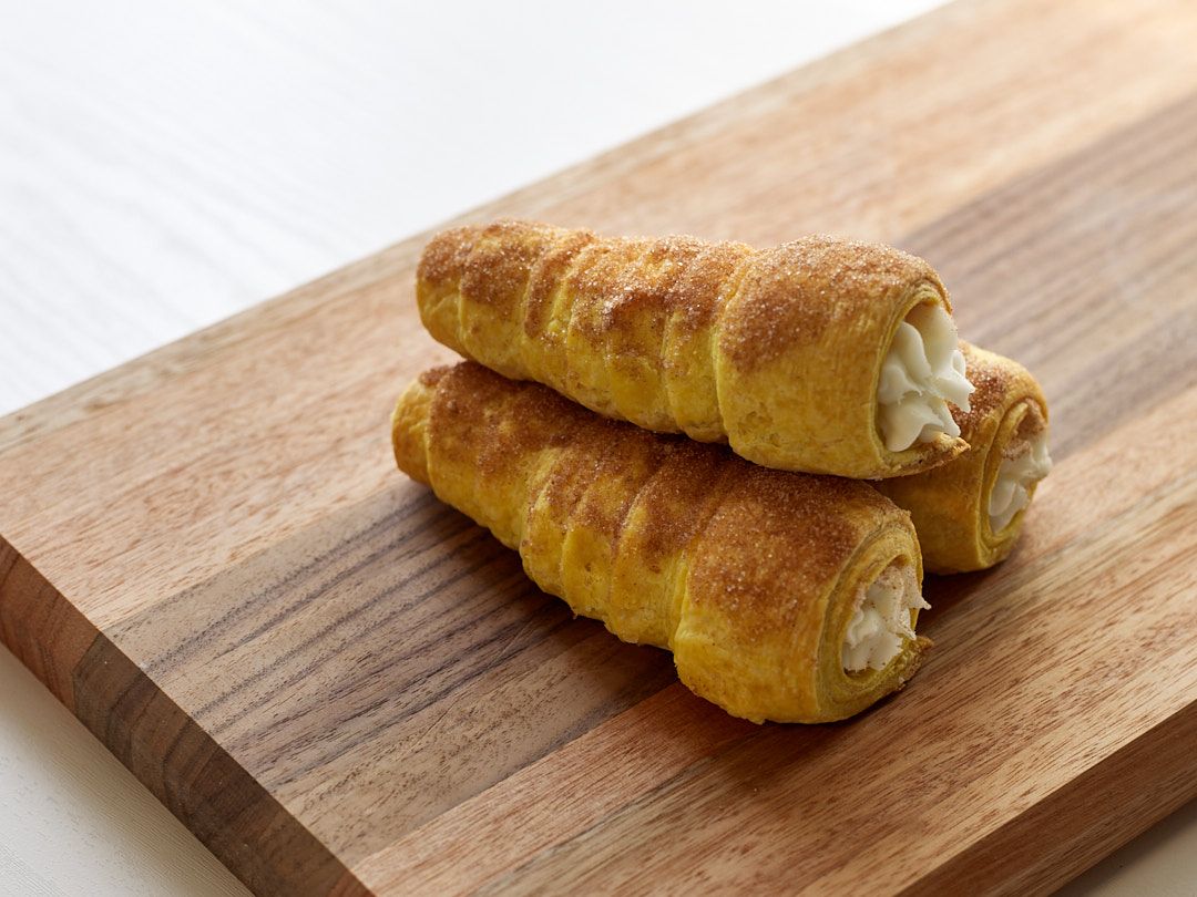 Fresh baked croissants with flaky golden layers displayed on a wooden cutting board.