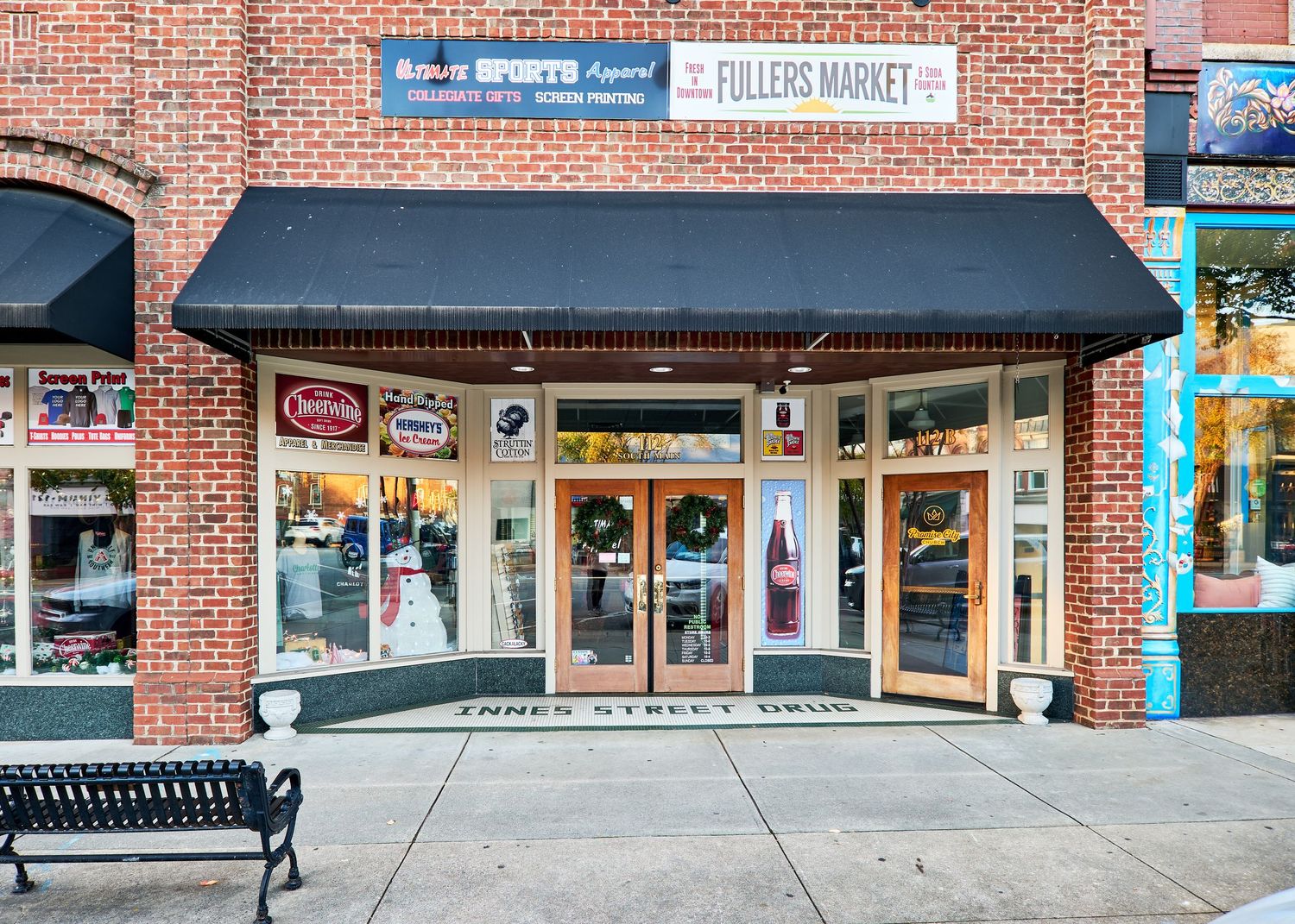 Storefront with black awning and brick exterior features a welcoming entrance and display windows in a downtown setting.