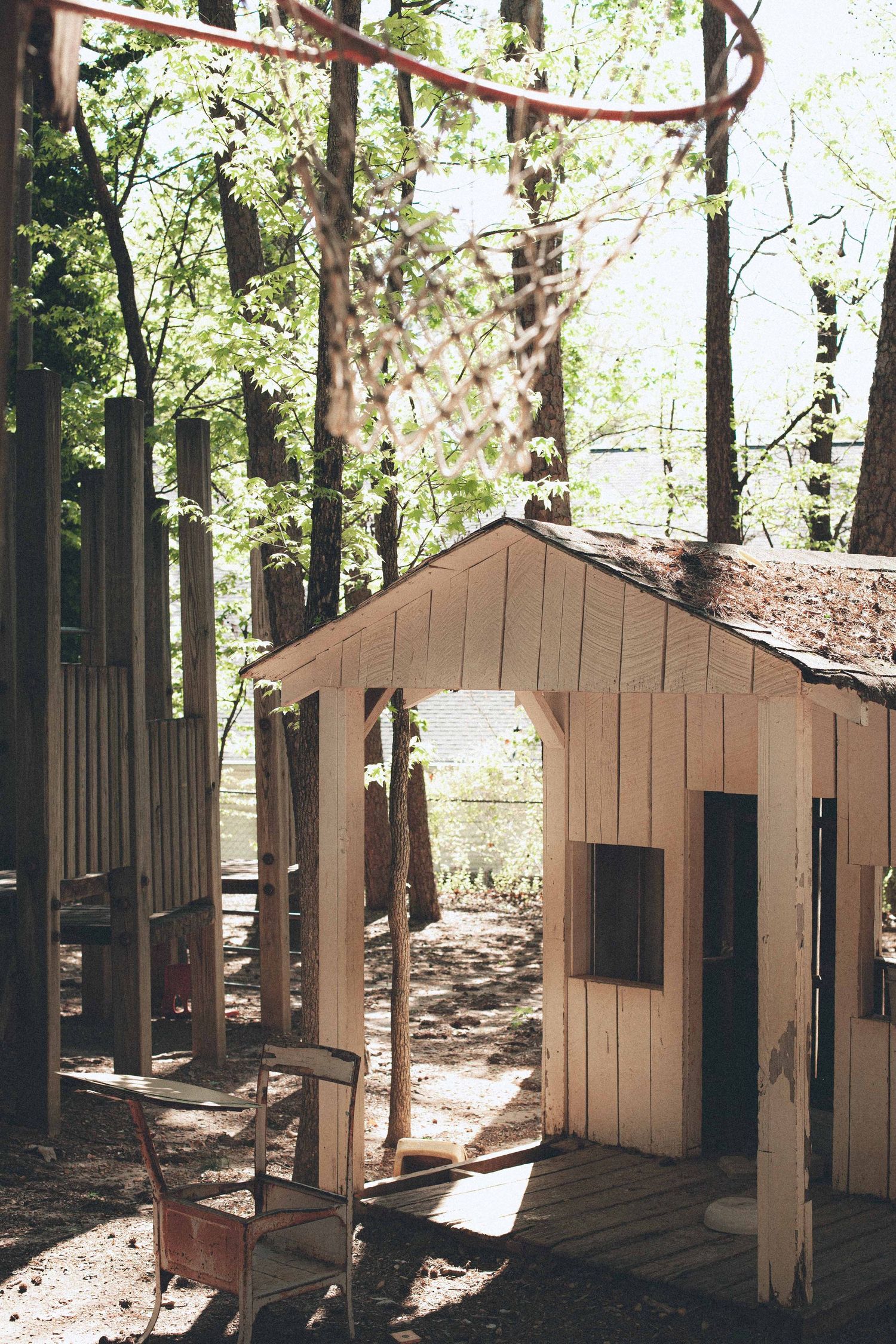 Tan wooden cabin structures arranged in a row along a wooded path.