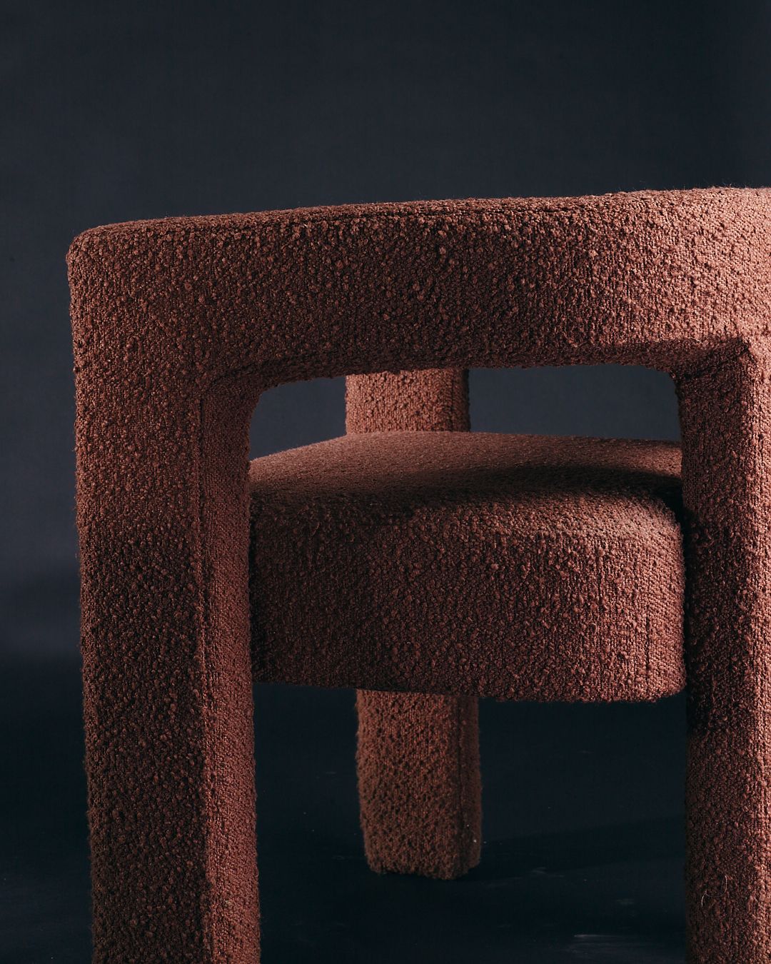 Abstract architectural forms cast dramatic shadows against a textured brown surface in a minimalist composition.
