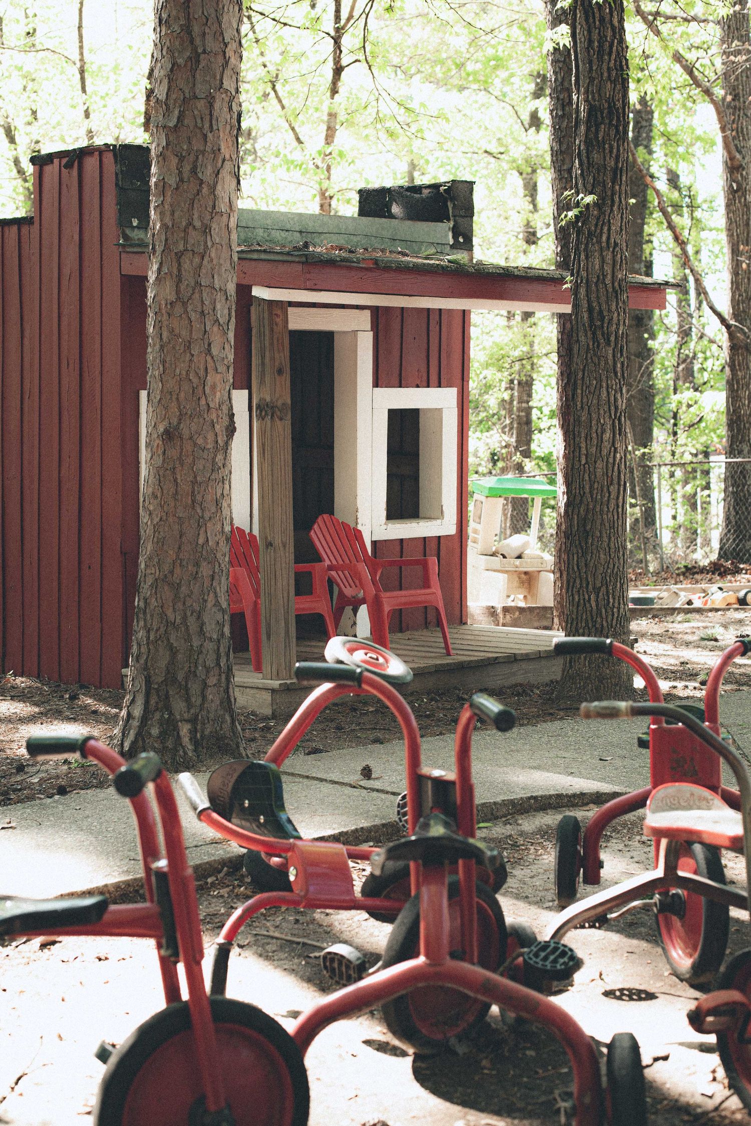 Red spring riders and playground equipment outside rustic brown cabins in a wooded setting.