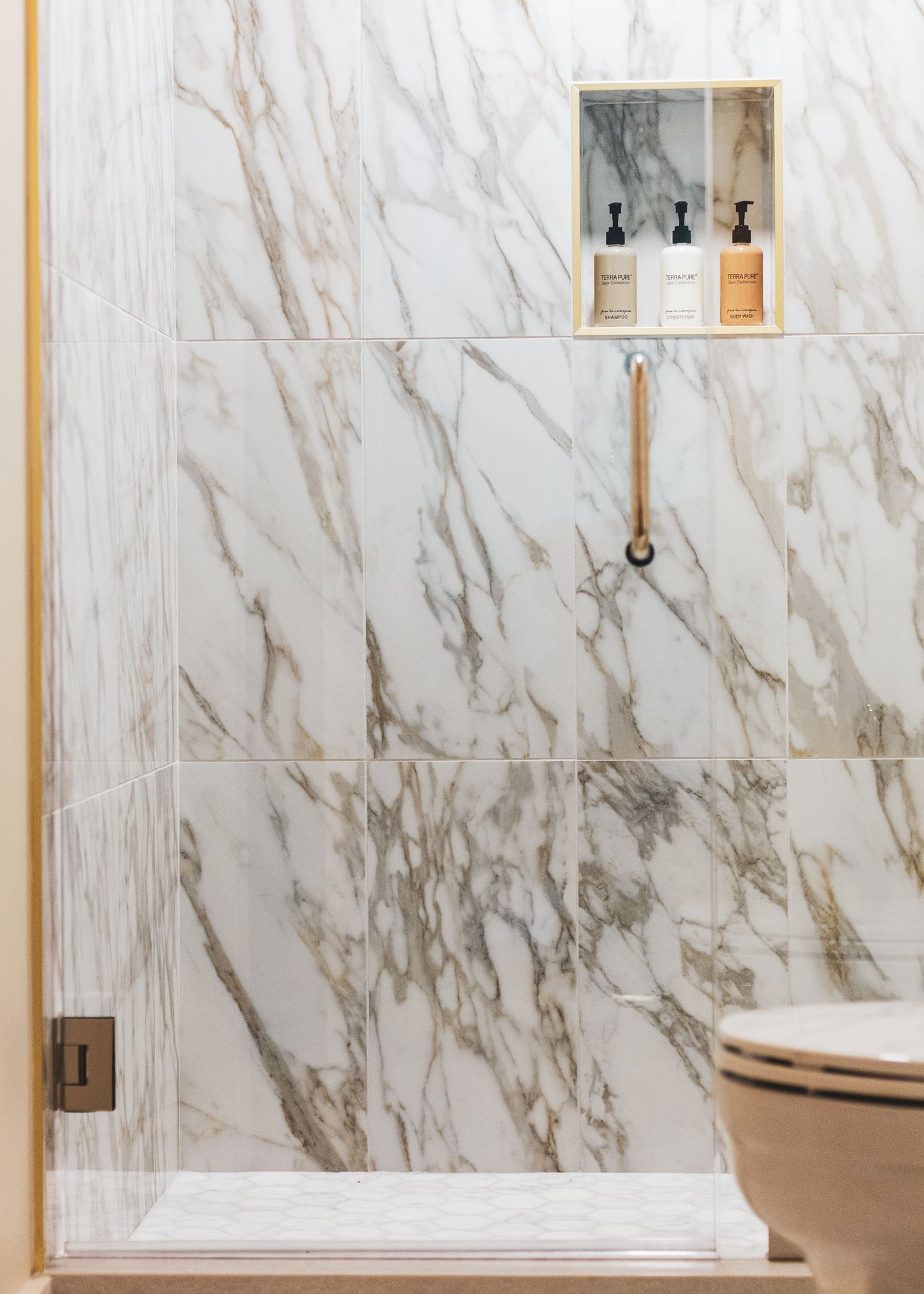 Modern bathroom interior with white marble walls, wooden accents, and sleek fixtures creating an elegant spa-like atmosphere.