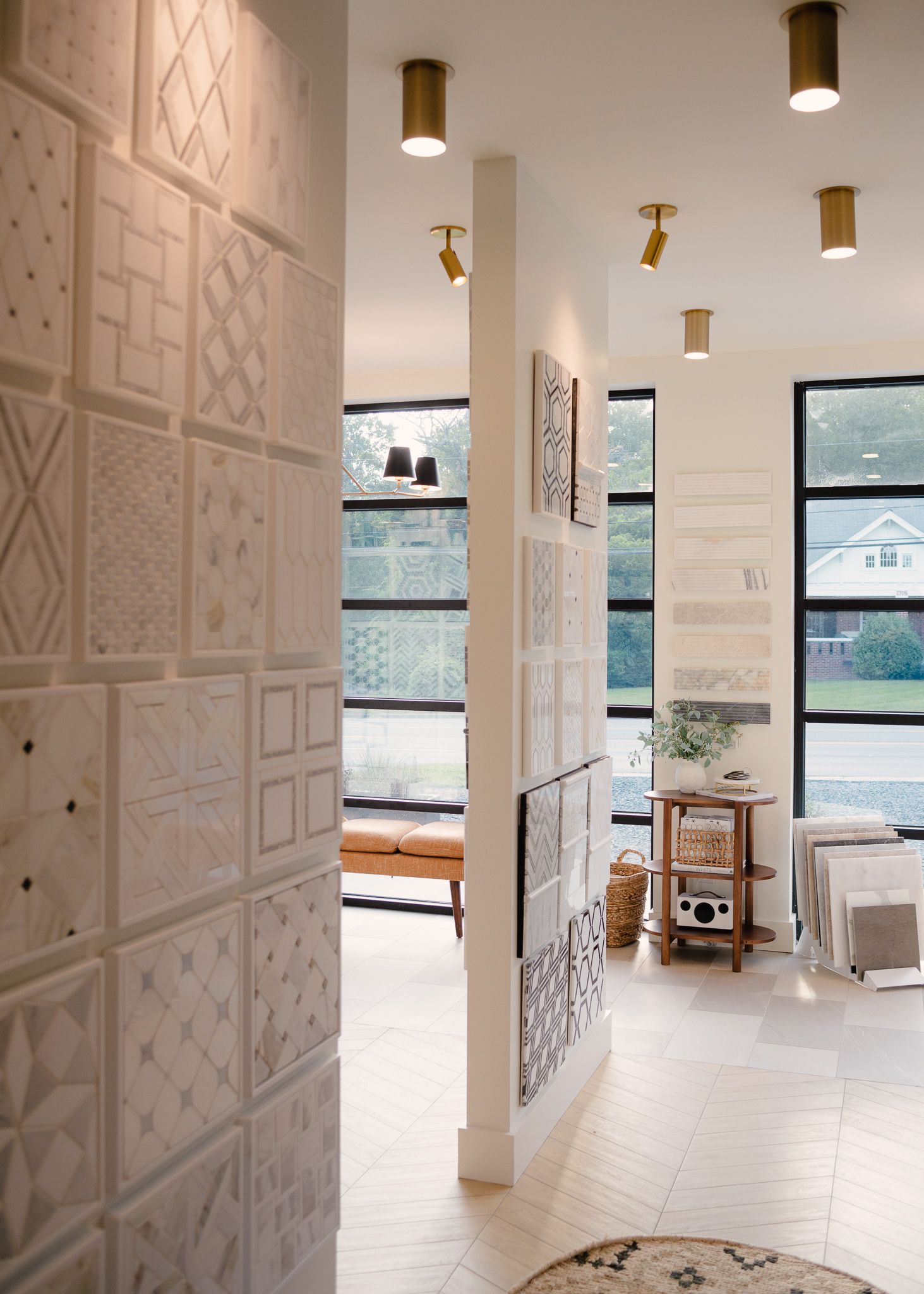 Modern interior space with geometric wall paneling, gold pendant lights, and large windows showcasing a bright, open layout.
