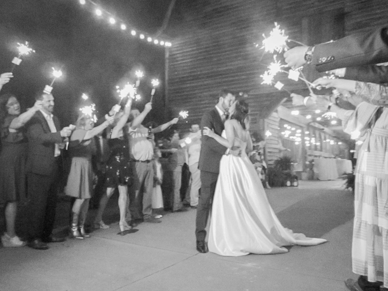 Black and white wedding reception photos showing guests creating a sparkler exit tunnel.