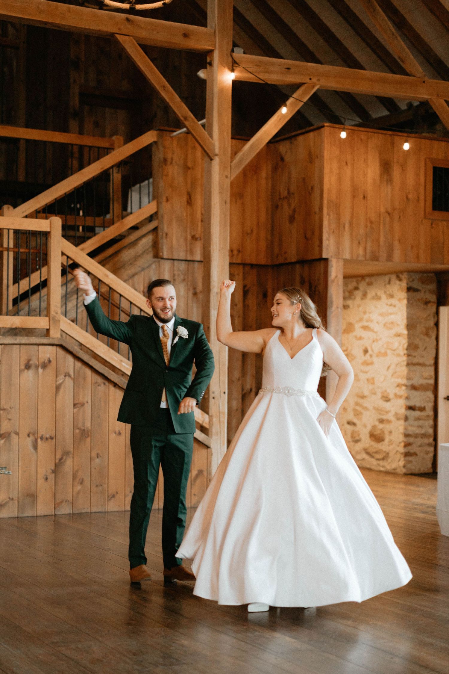 A couple shares a playful dance moment in a rustic wooden barn venue.
