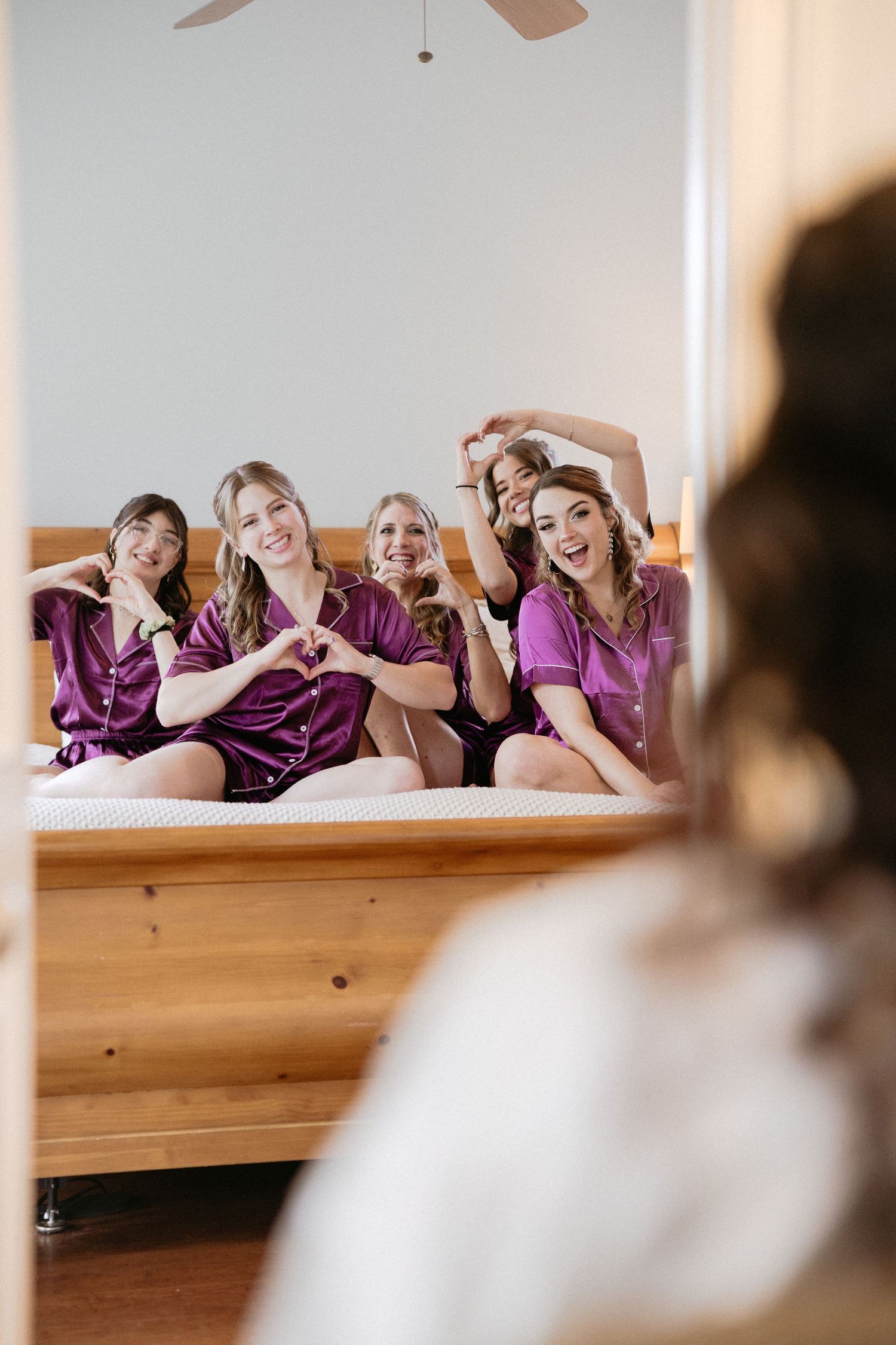 A group in matching purple satin robes pose playfully together on a wooden bench.