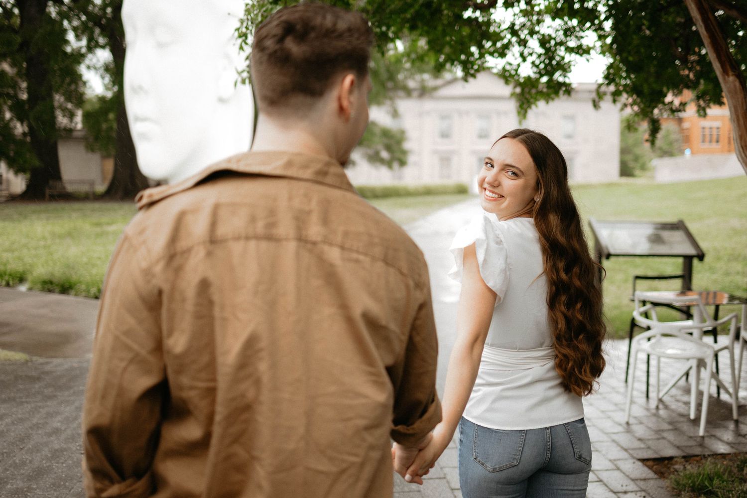 Engaged couple walking along outdoor path during romantic wedding photo shoot at rustic venue.