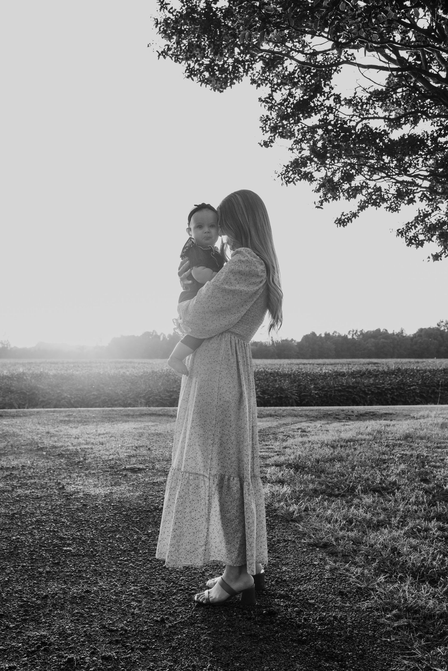A figure in a white dress walks through a misty field at sunset creating a dreamy black and white silhouette.