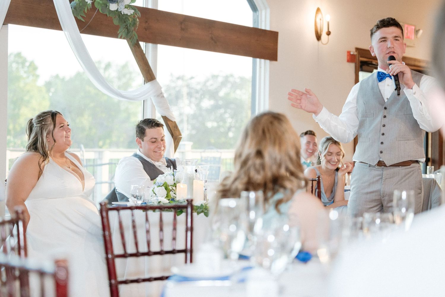 Wedding reception venue with elegant table settings and natural lighting.