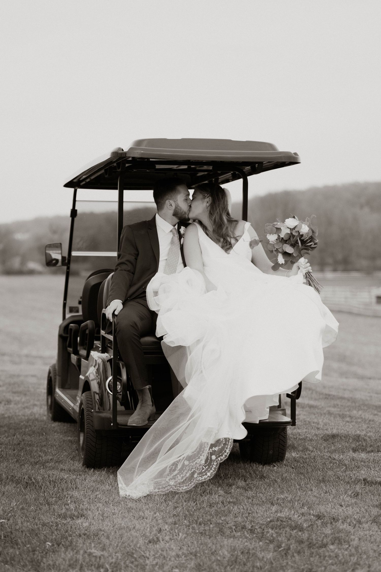 Black and white photos of newlyweds riding in golf cart across wedding venue grounds.