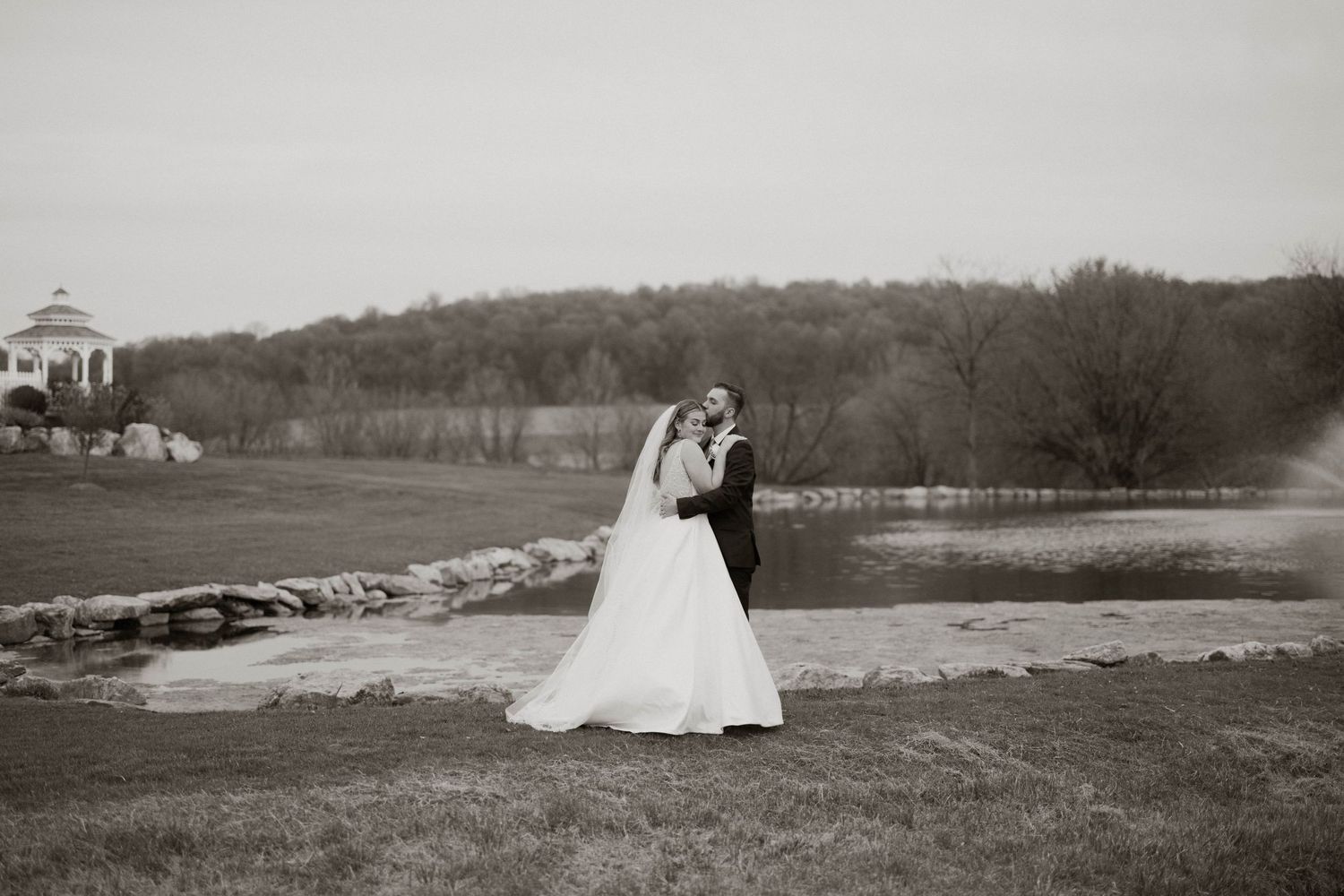 Newlyweds pose for romantic portraits in scenic countryside with rolling hills and historic buildings.