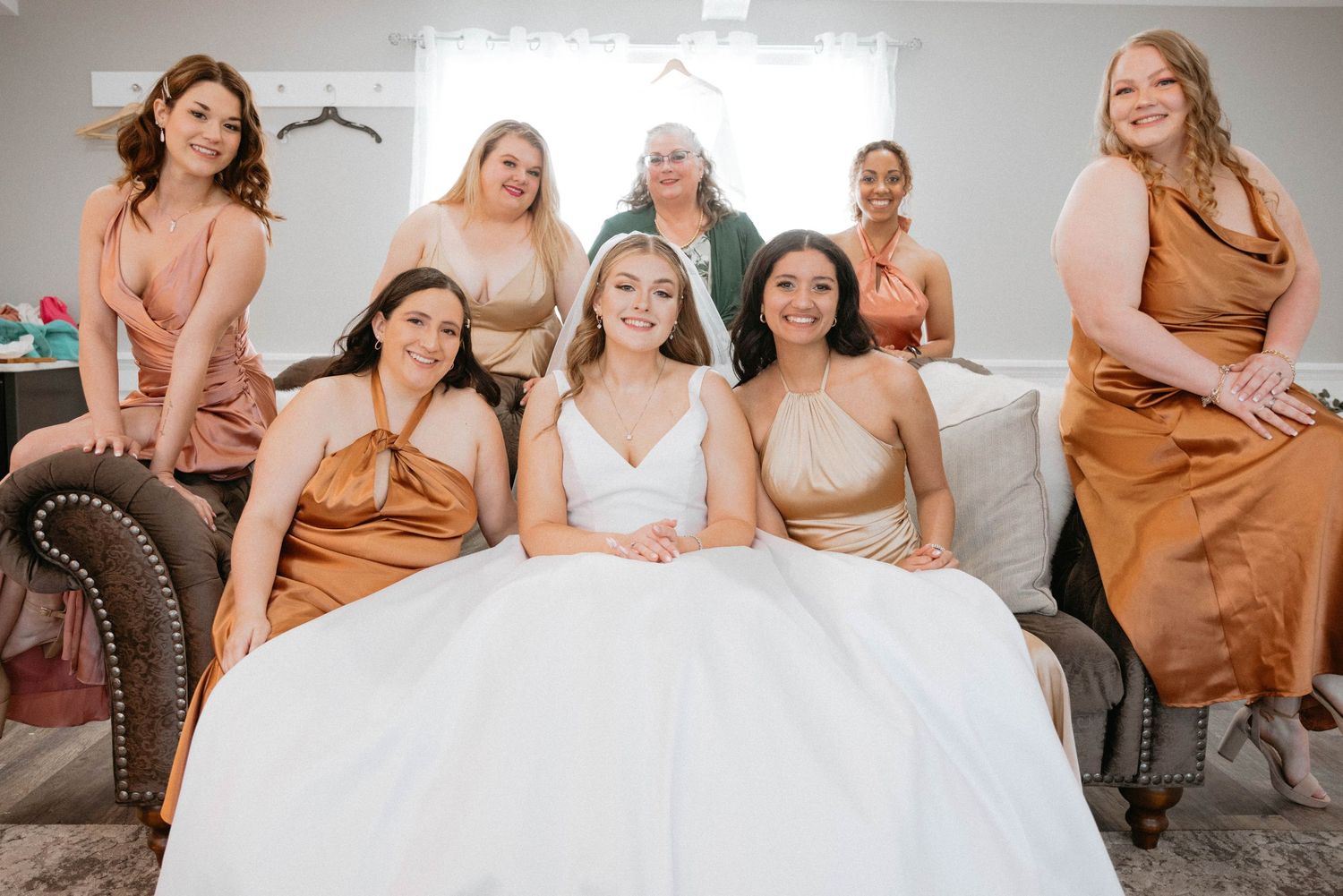 Group of people wearing earth-toned dresses pose together for a casual photoshoot.