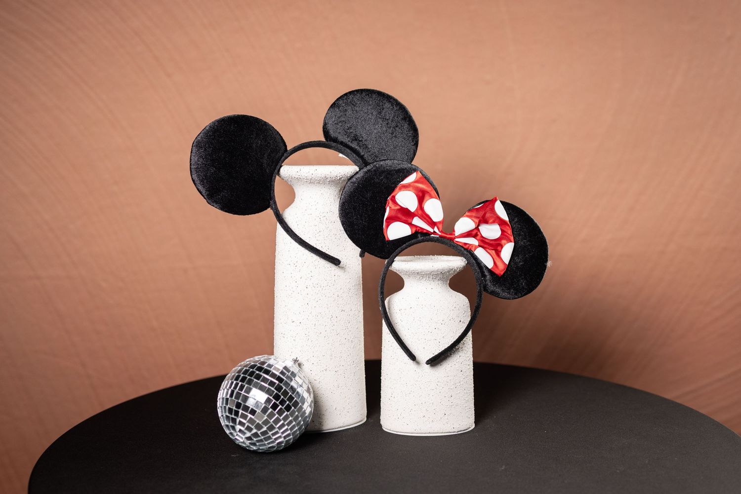 Various accessories and props including sunglasses, mouse ears, and a disco ball against a brown background.