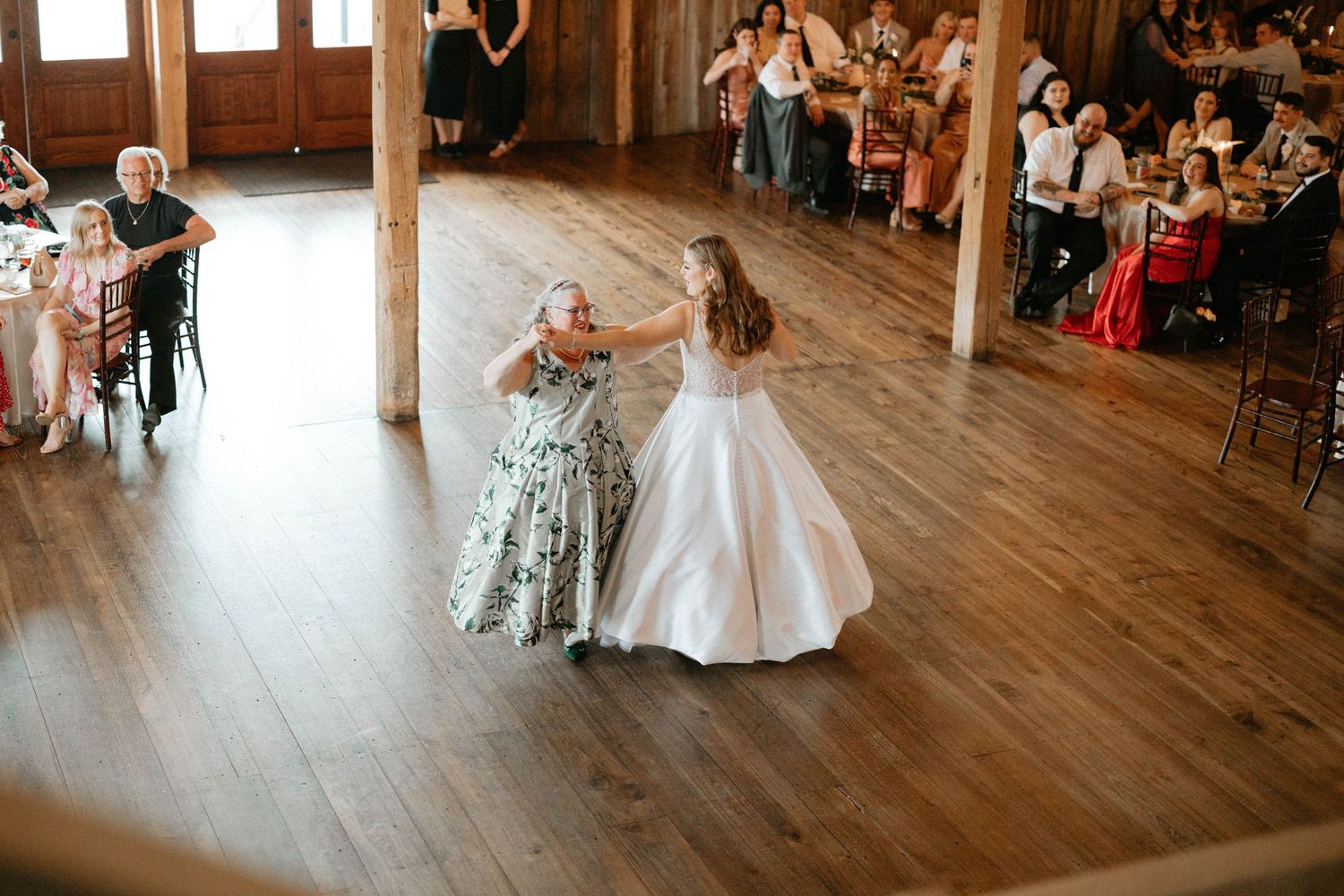 Couple shares romantic first dance on wooden floor at rustic barn wedding reception.
