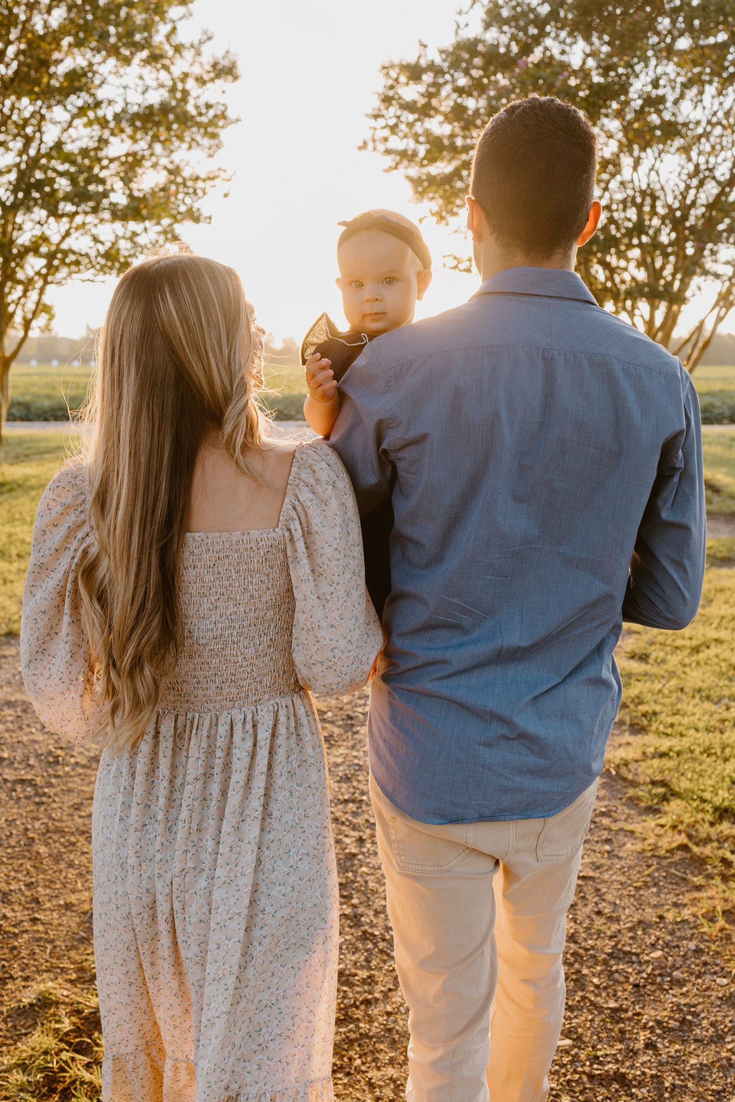 A couple in casual attire holding hands and walking during golden hour sunset in a park setting.