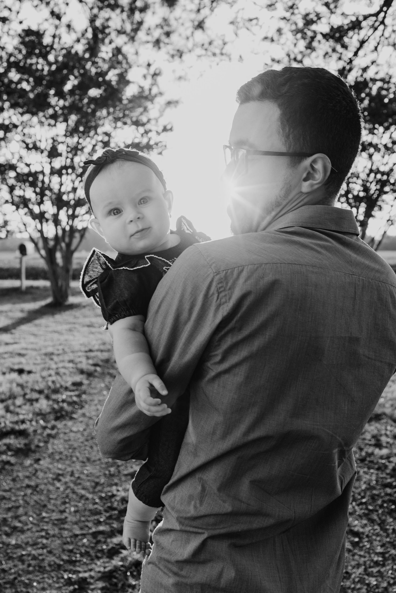 Black and white series of candid shots showing tender parent-child moment during outdoor photoshoot in natural setting.