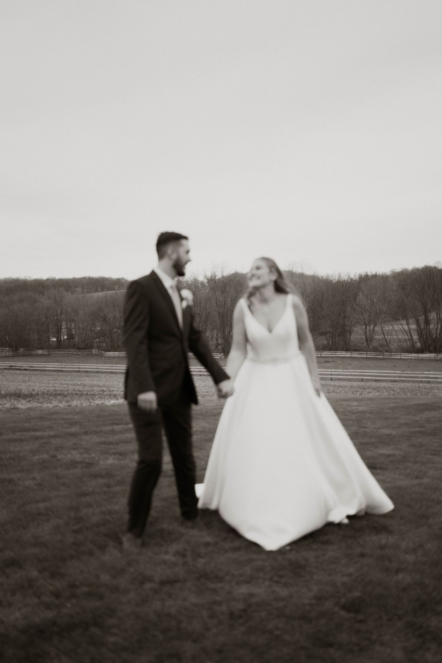Black and white sequence of newlyweds walking playfully across an open field.