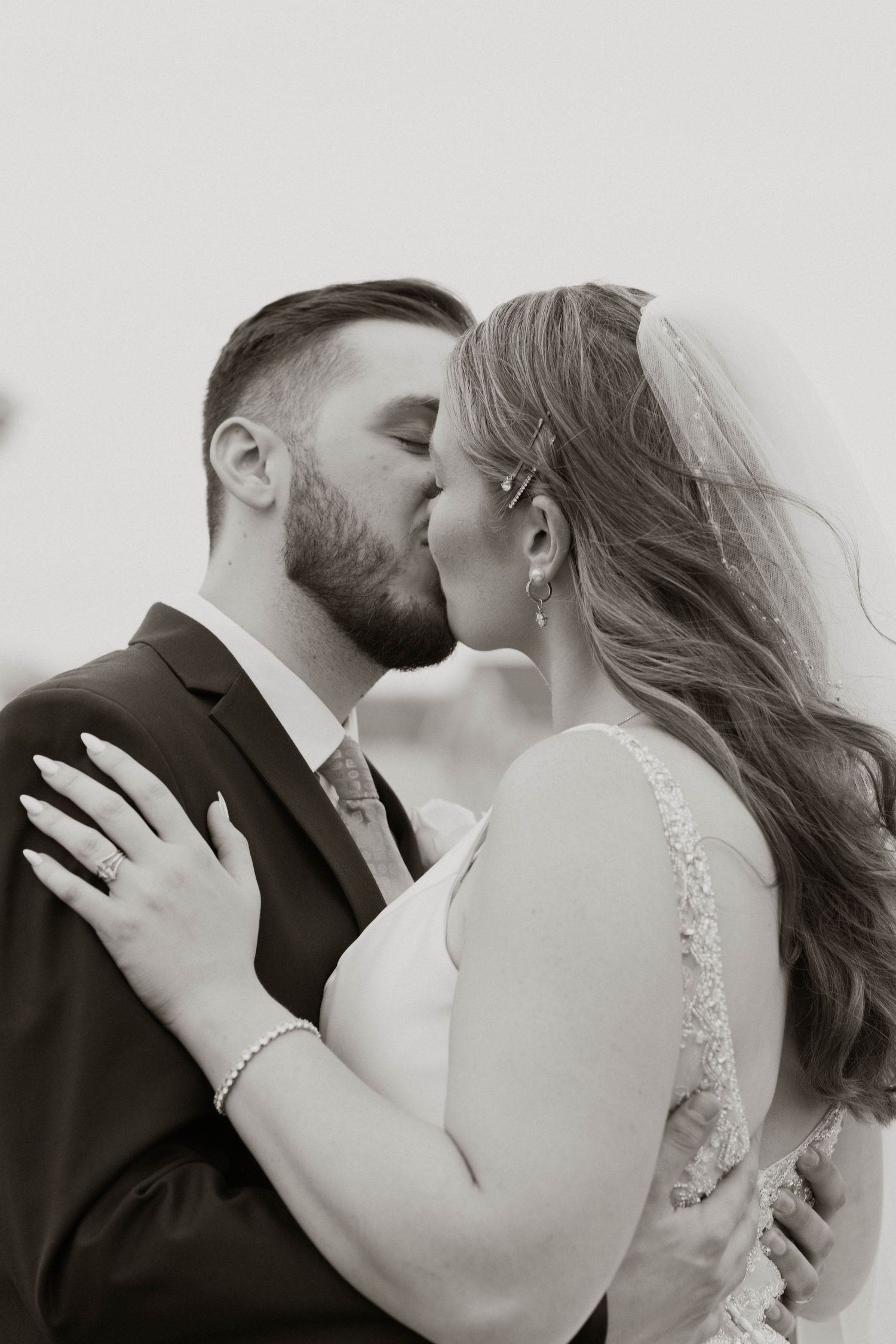 A romantic black and white wedding photography sequence showing a close-up kiss between newlyweds.