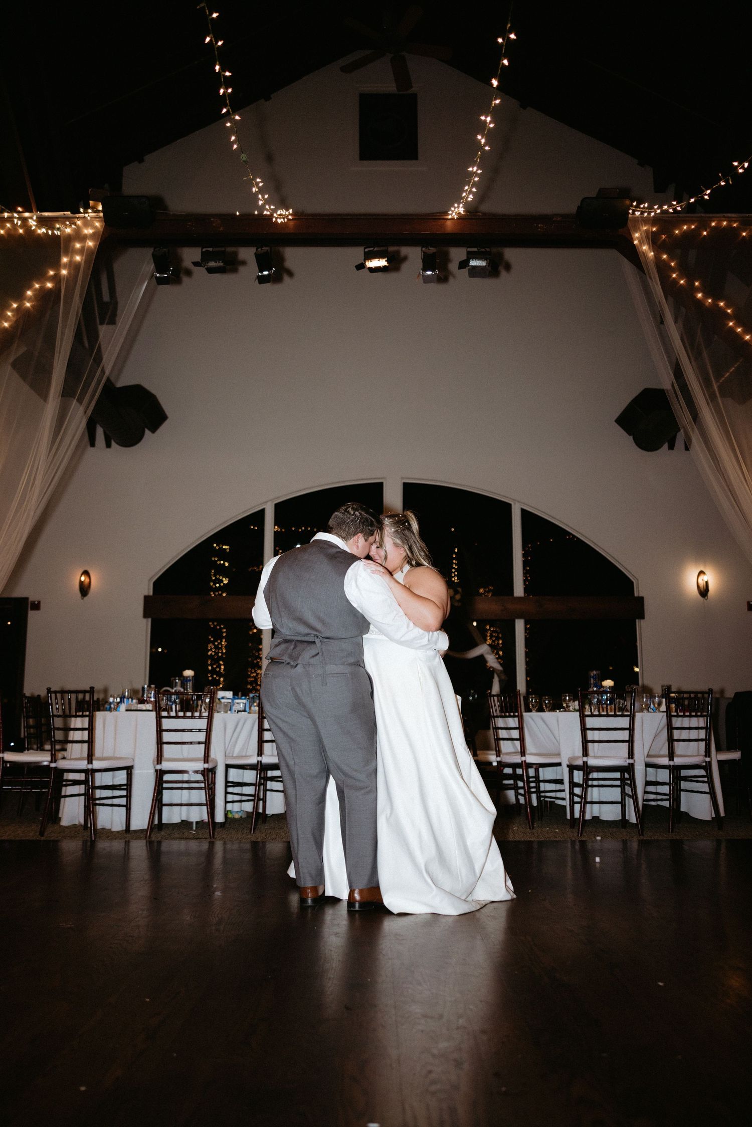 Indoor wedding reception venue with string lights and dark ambiance.