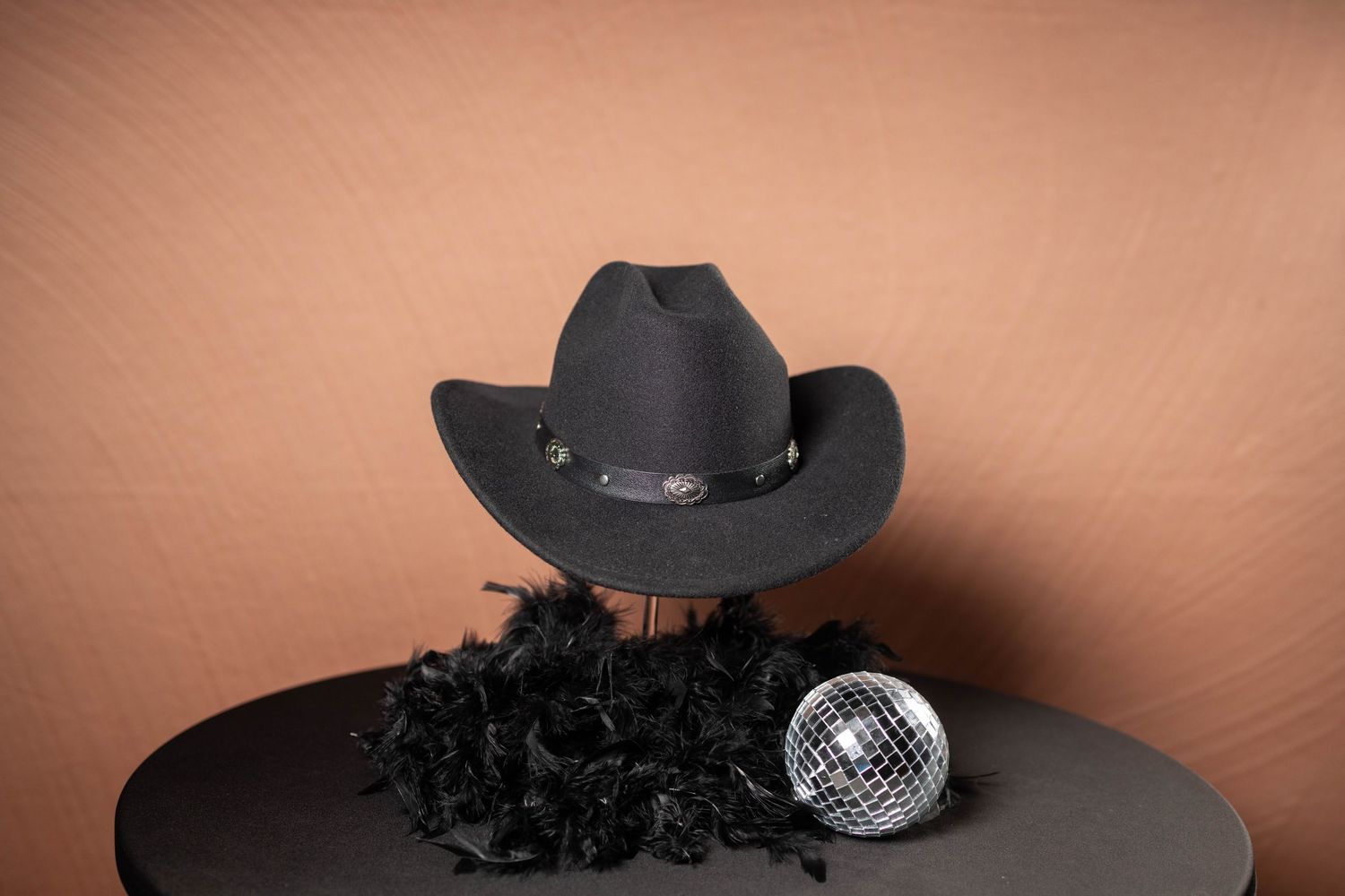 Black cowboy hat displayed next to a silver disco ball and white decorative items.