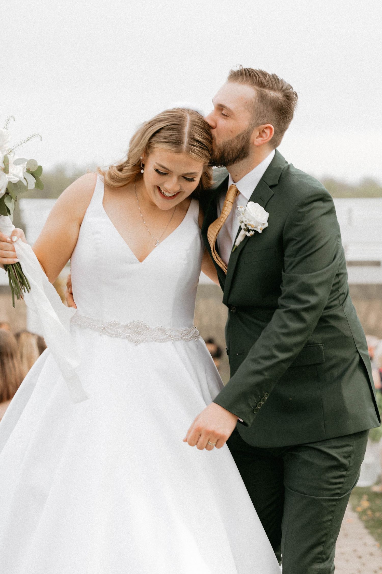 A joyful wedding couple sharing an intimate moment outdoors.