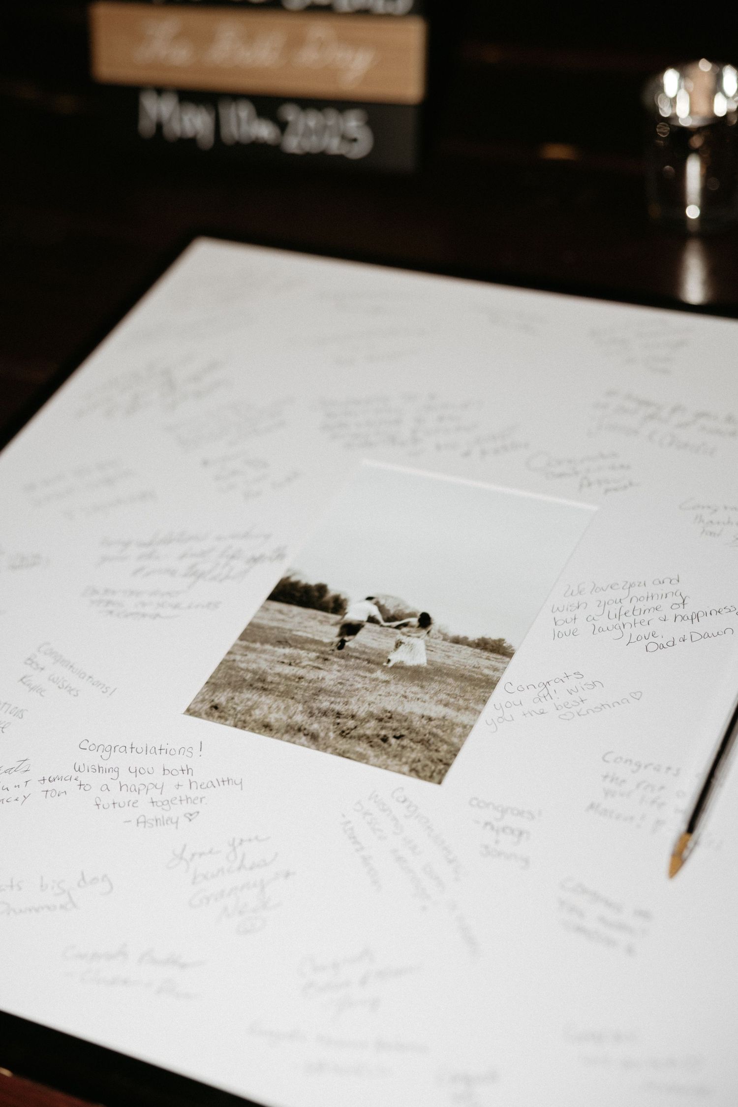 Guest book page with vintage photo and handwritten messages spread across white paper.