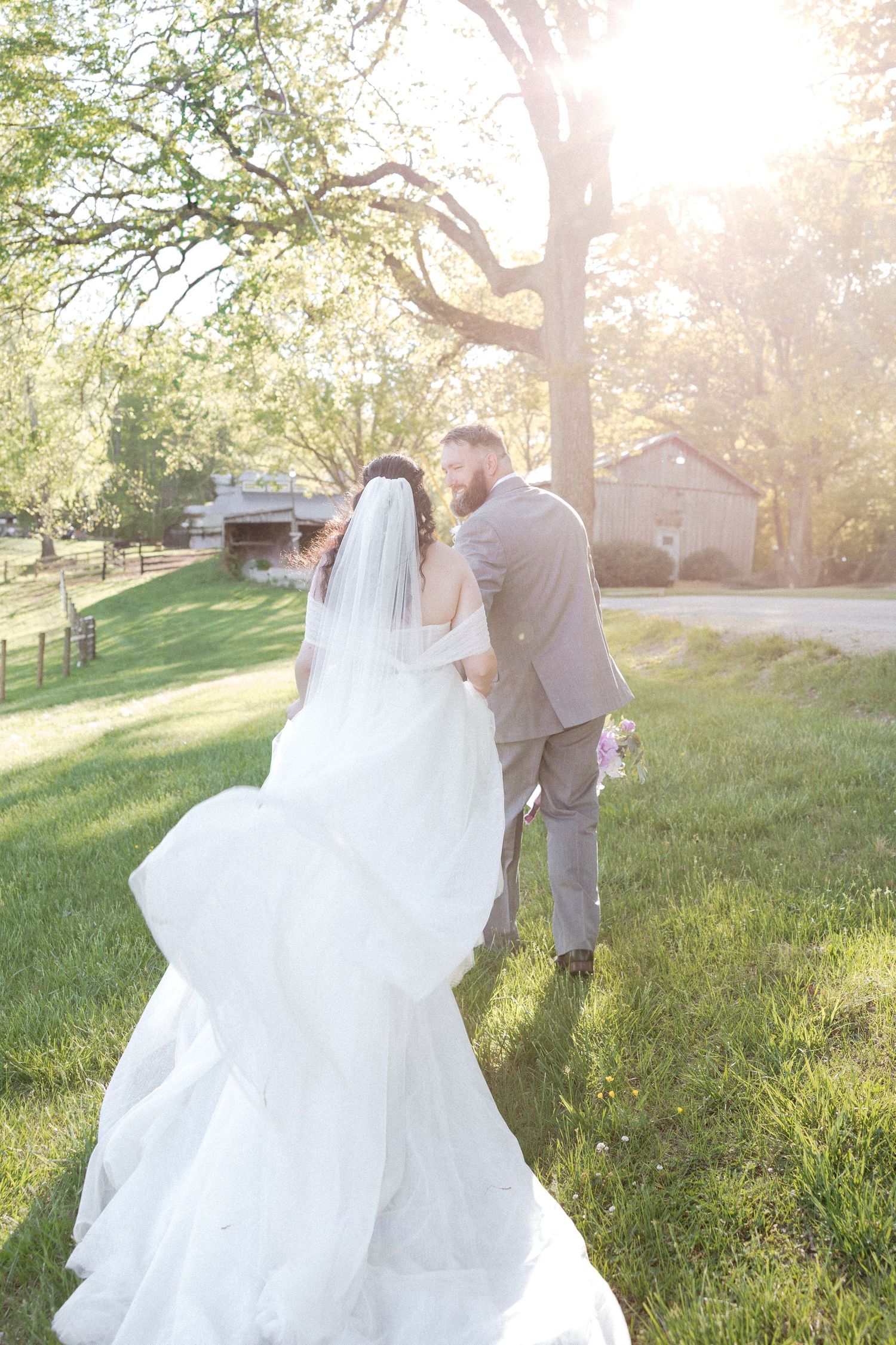 A romantic sunset photoshoot on a grassy hill with sunlight streaming through trees.