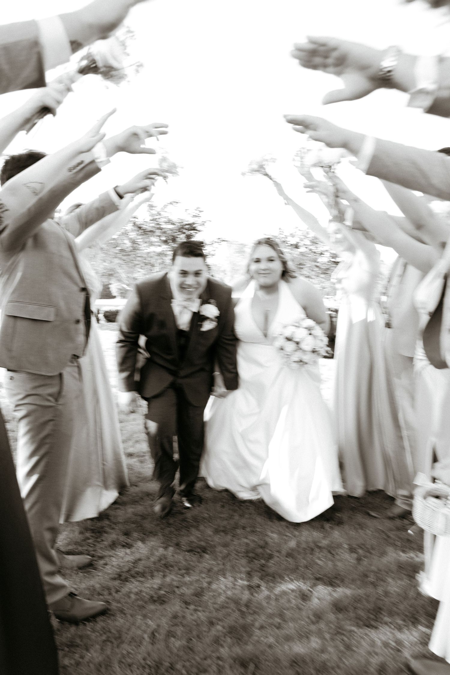 Wedding guests form an arch with raised hands for the newlyweds to walk through.