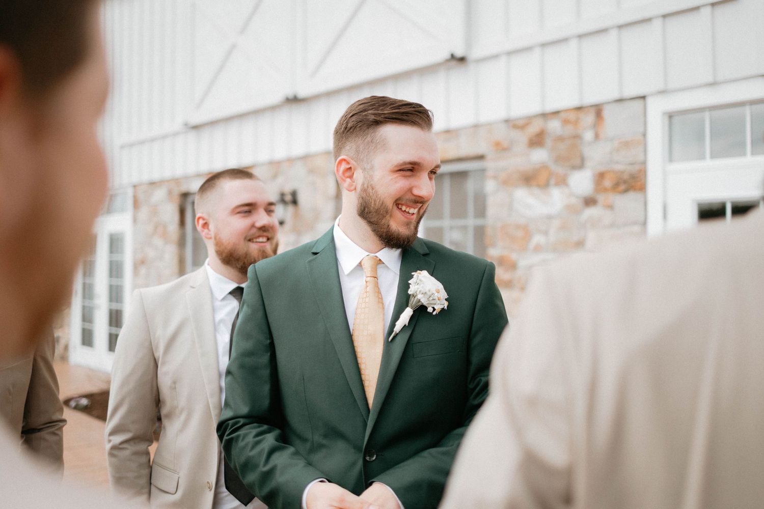 Members of a wedding party share joyful moments together in front of a brick wall.
