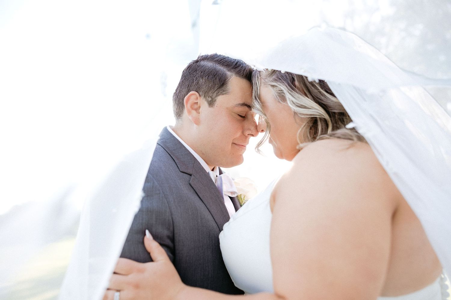 Romantic black and white close up portrait of newlyweds sharing an intimate moment with a sheer veil.