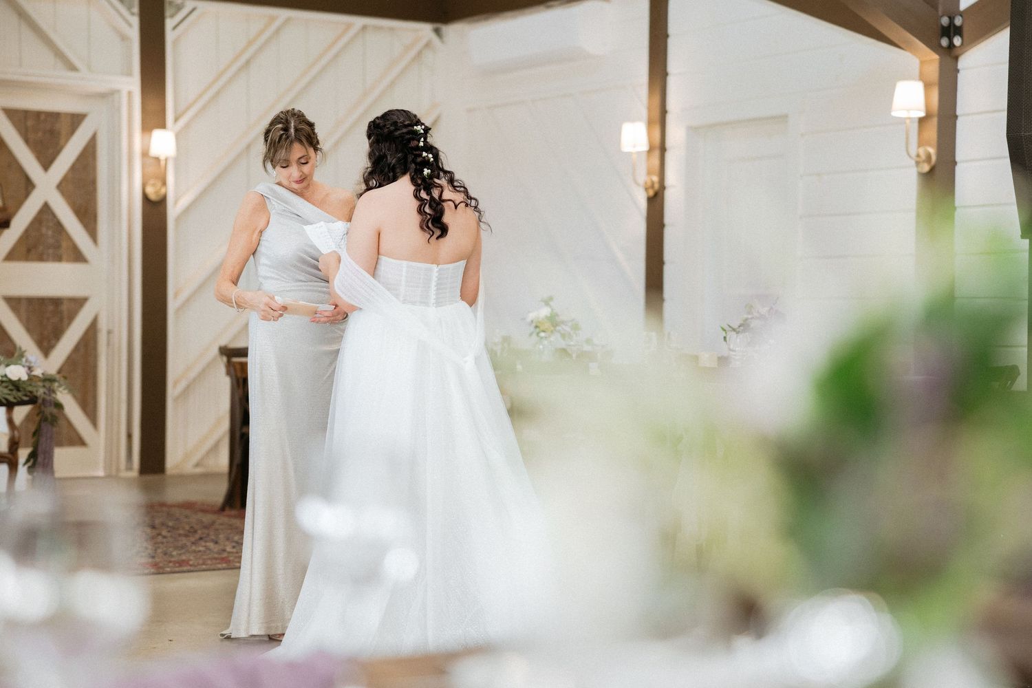 Two people in wedding attire standing together in an elegant white and wood-paneled room during a ceremony.