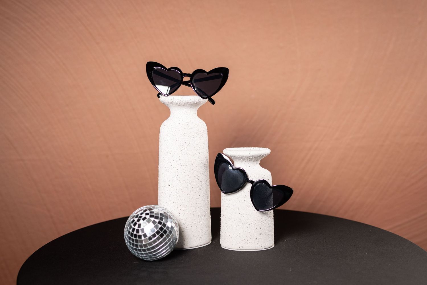 Heart-shaped sunglasses and Disney accessories displayed with white decorative elements.