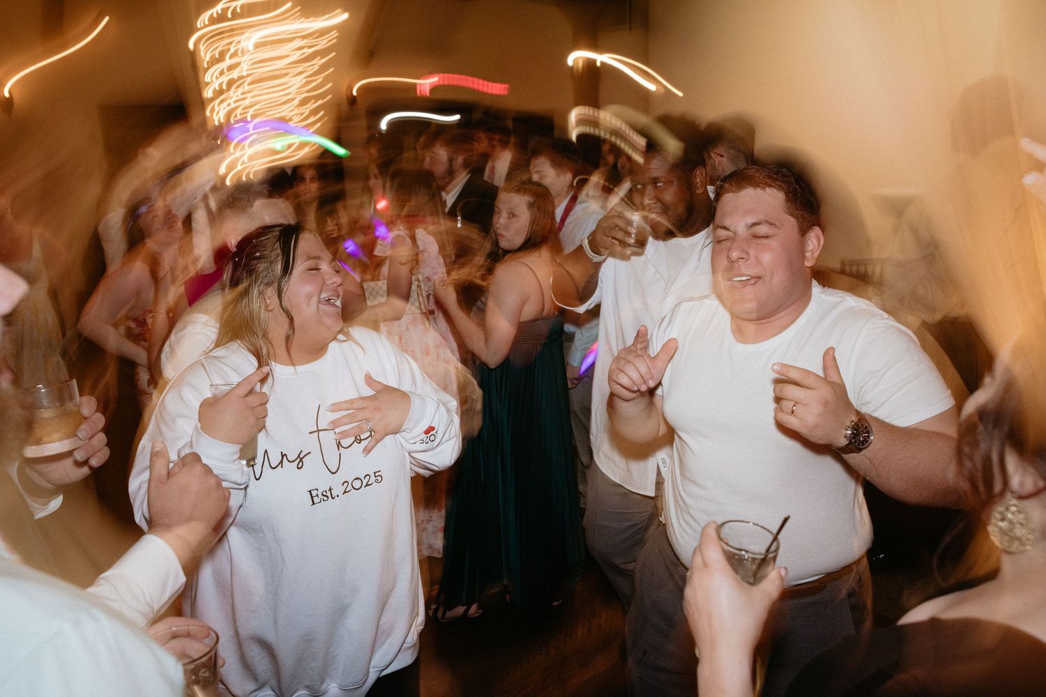 Dynamic reception dance floor moments captured with motion blur effects in warm lighting.