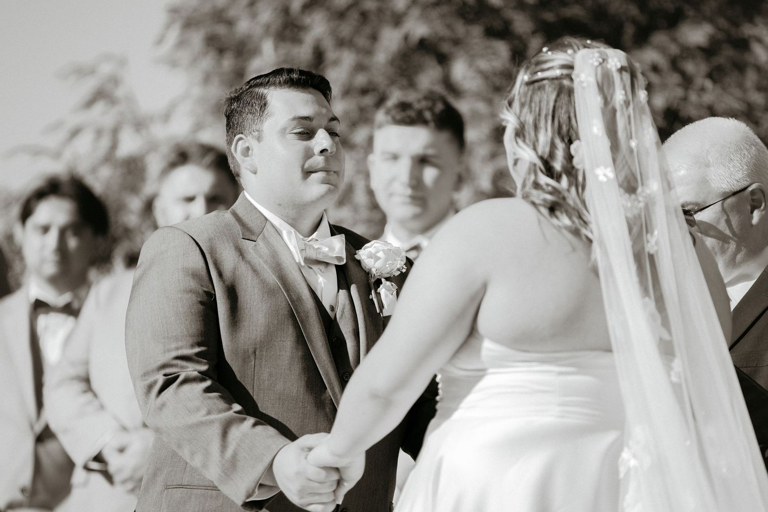 A couple exchanges wedding vows during an emotional outdoor ceremony with guests in attendance.