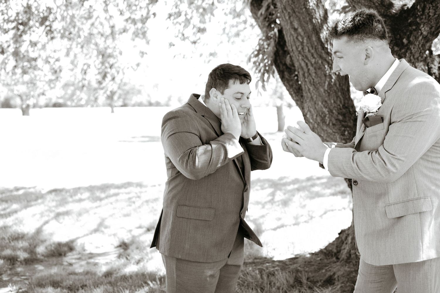 Two people share an emotional moment under a tree during what appears to be a wedding celebration.