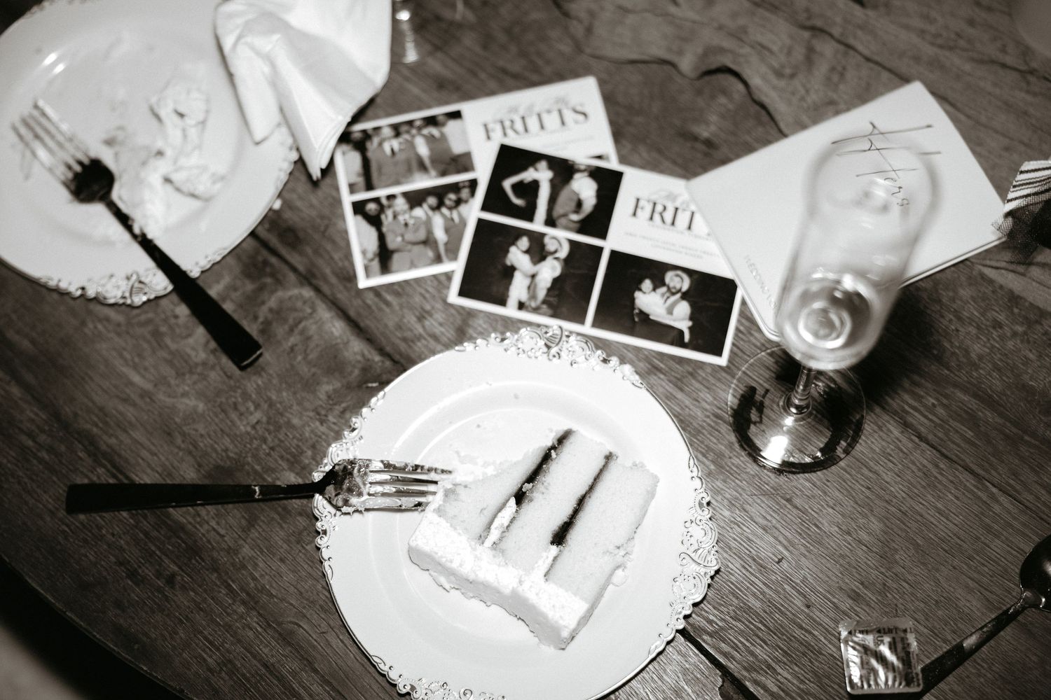 Black and white photo of vintage photographs and memorabilia scattered on a wooden table.
