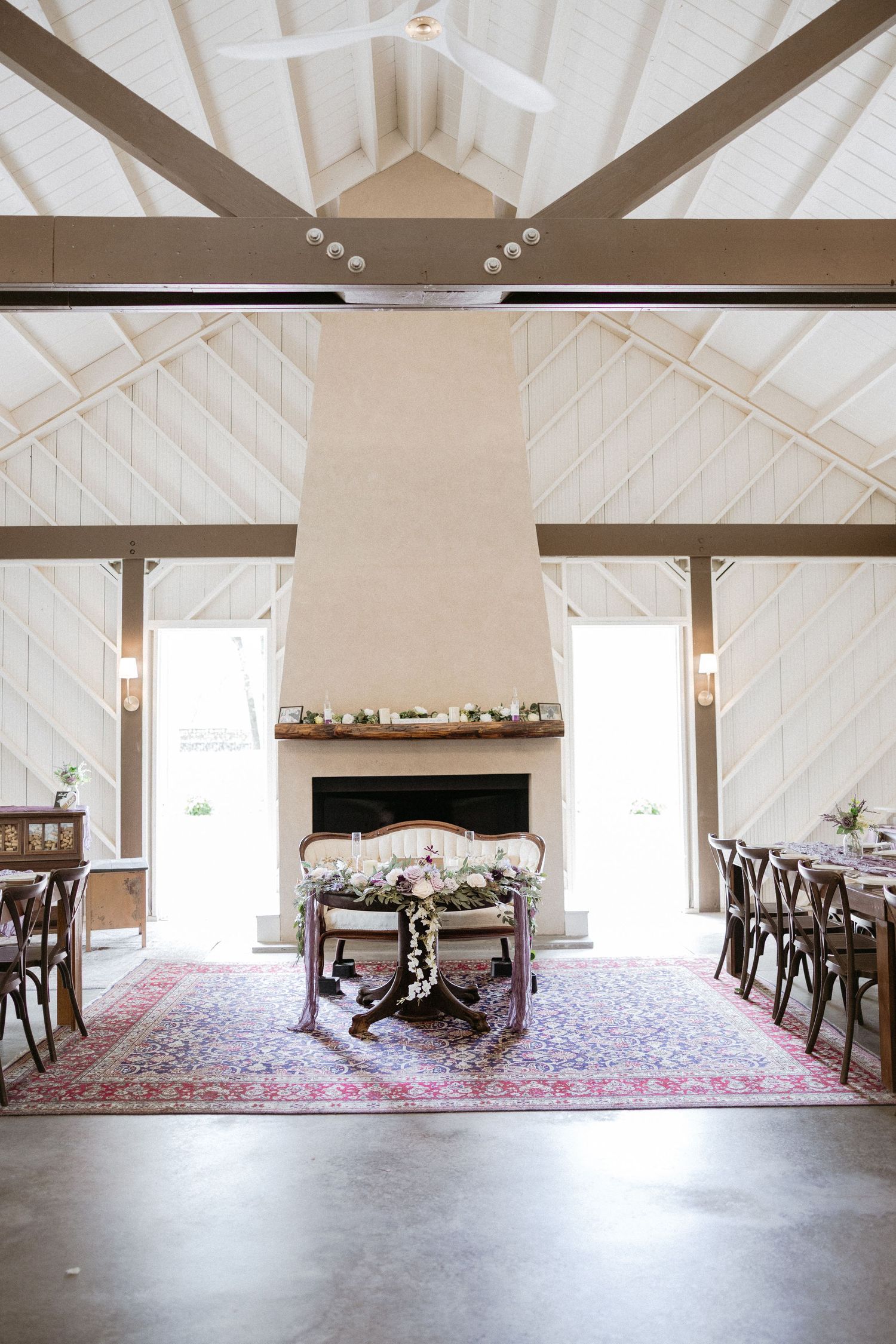 Interior view of a rustic white room with exposed wooden beams and a decorative oriental rug on the floor.