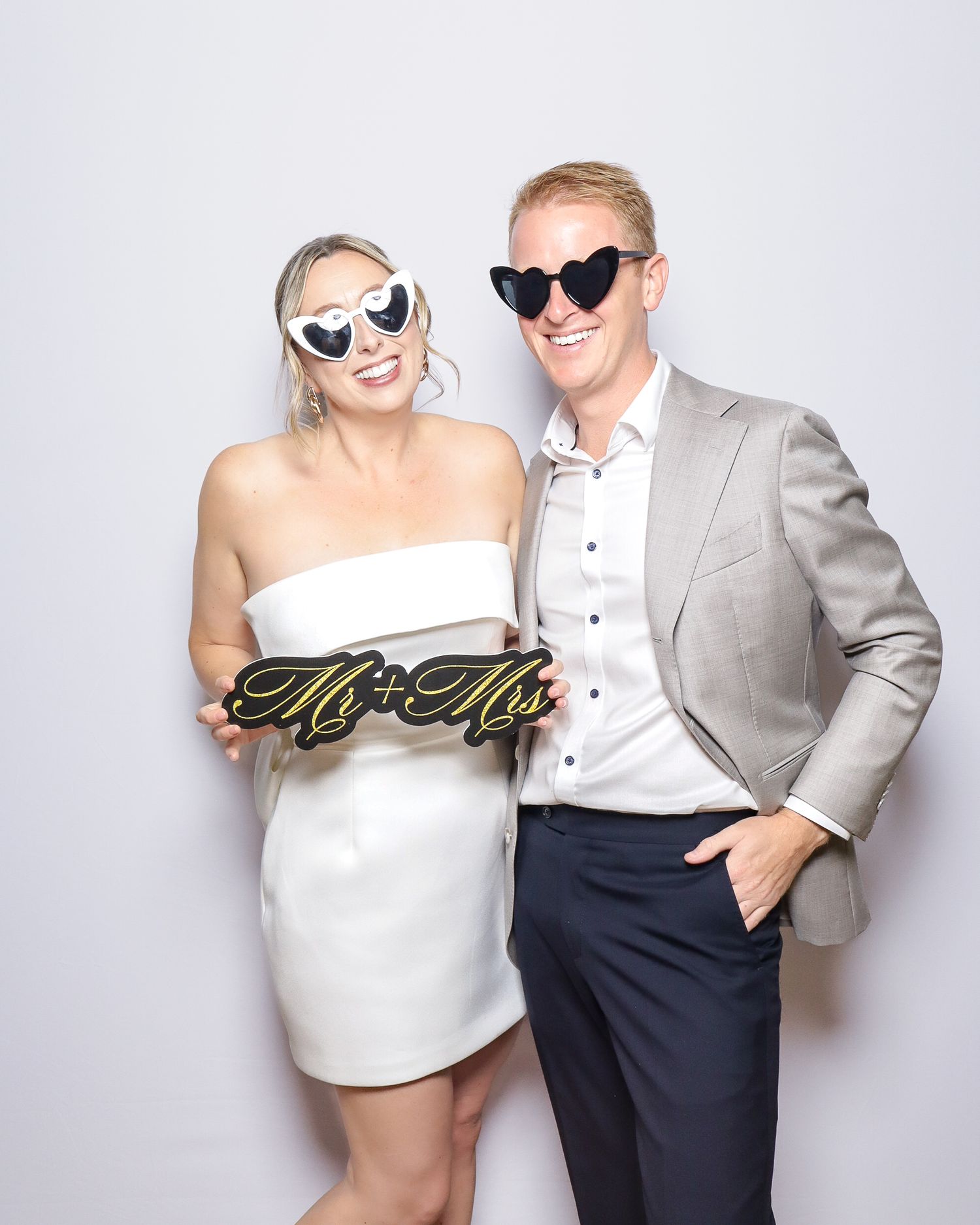 A couple wearing formal attire poses playfully in a series of black and white photo booth style shots.
