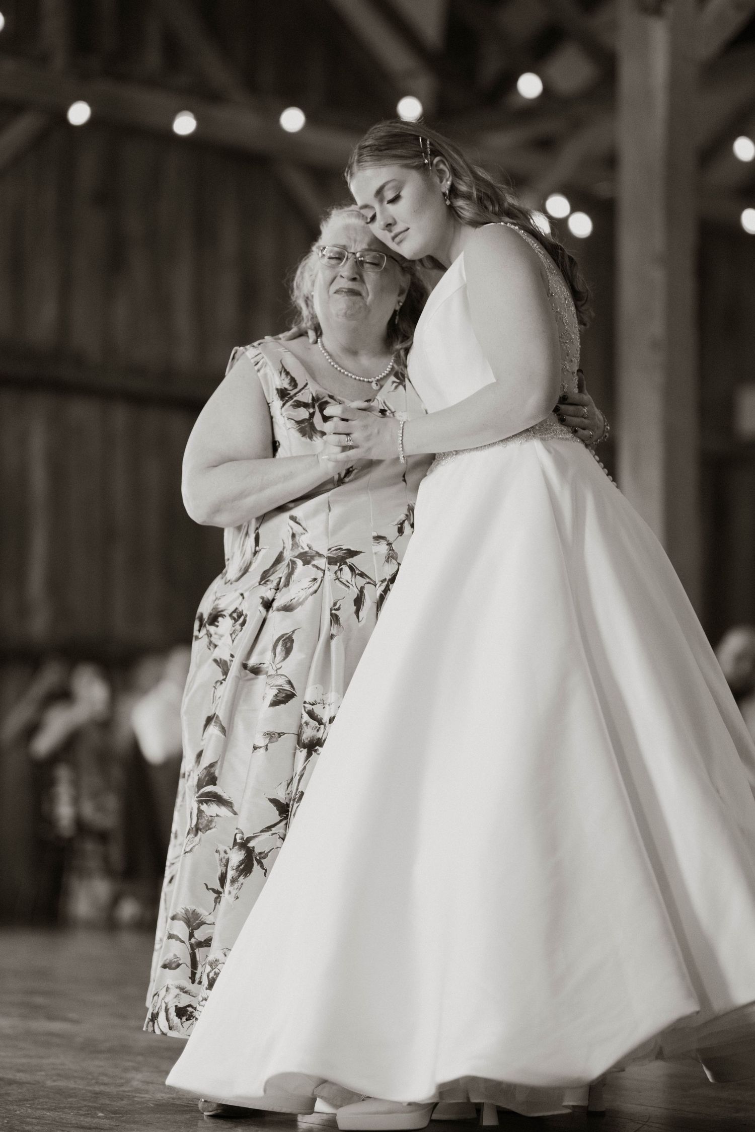 Black and white image of small children in formal attire dancing together at a wedding reception.