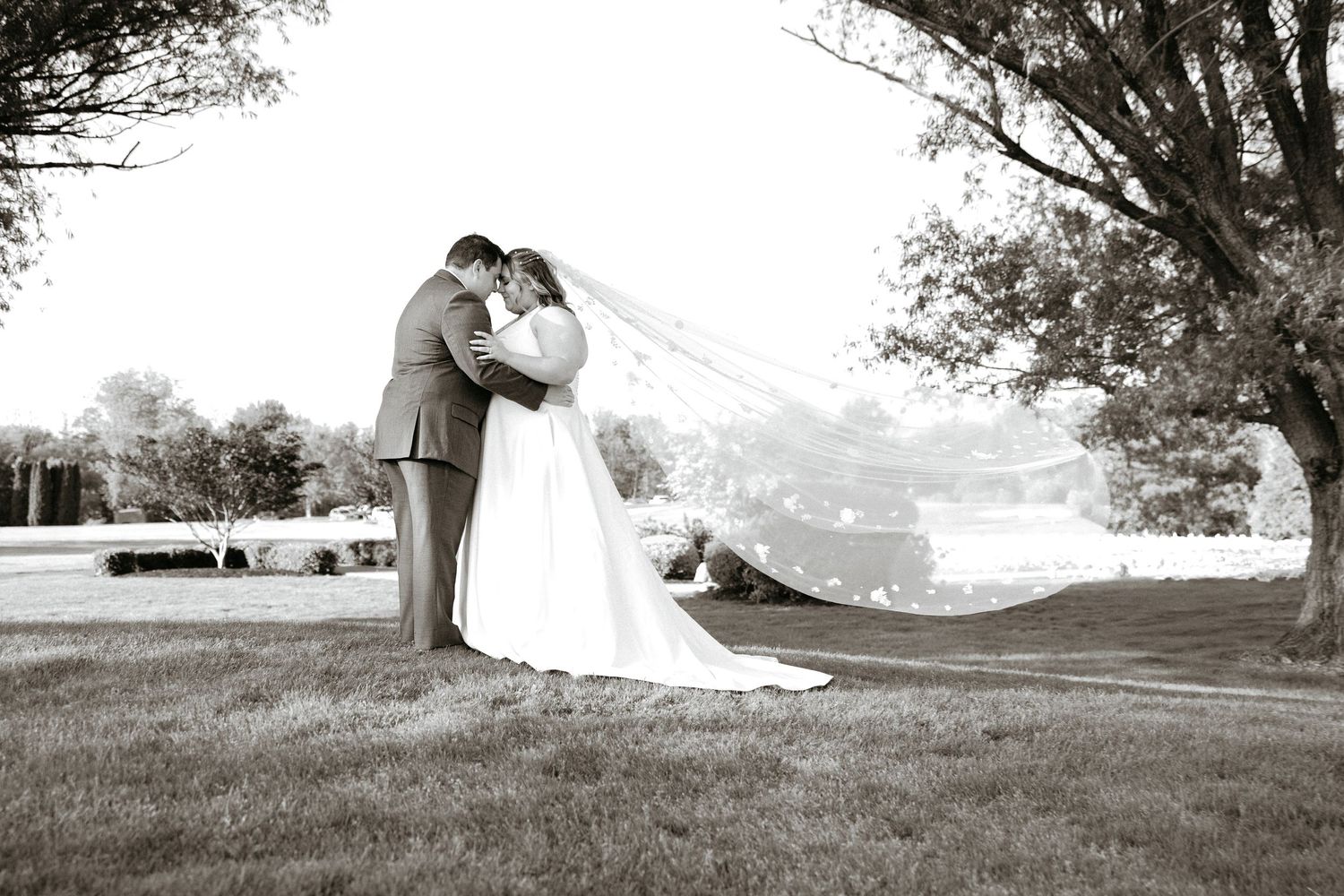 Romantic wedding photography session on a grassy hillside.