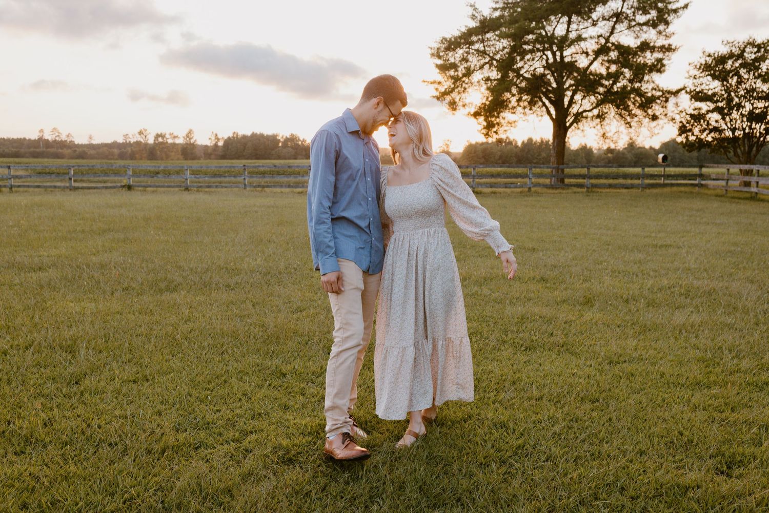 A couple shares a tender moment in a golden field at sunset, creating a romantic silhouette against the glowing sky.