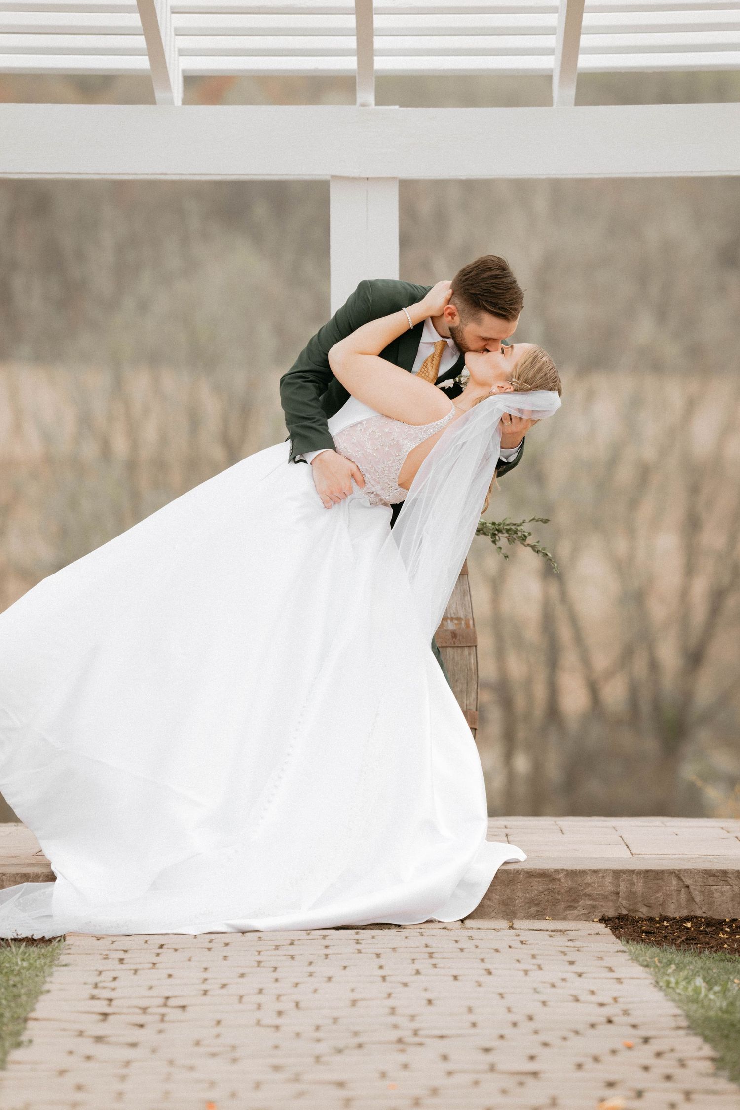A flowing white wedding dress twirls gracefully in an outdoor setting with autumn trees in the background.