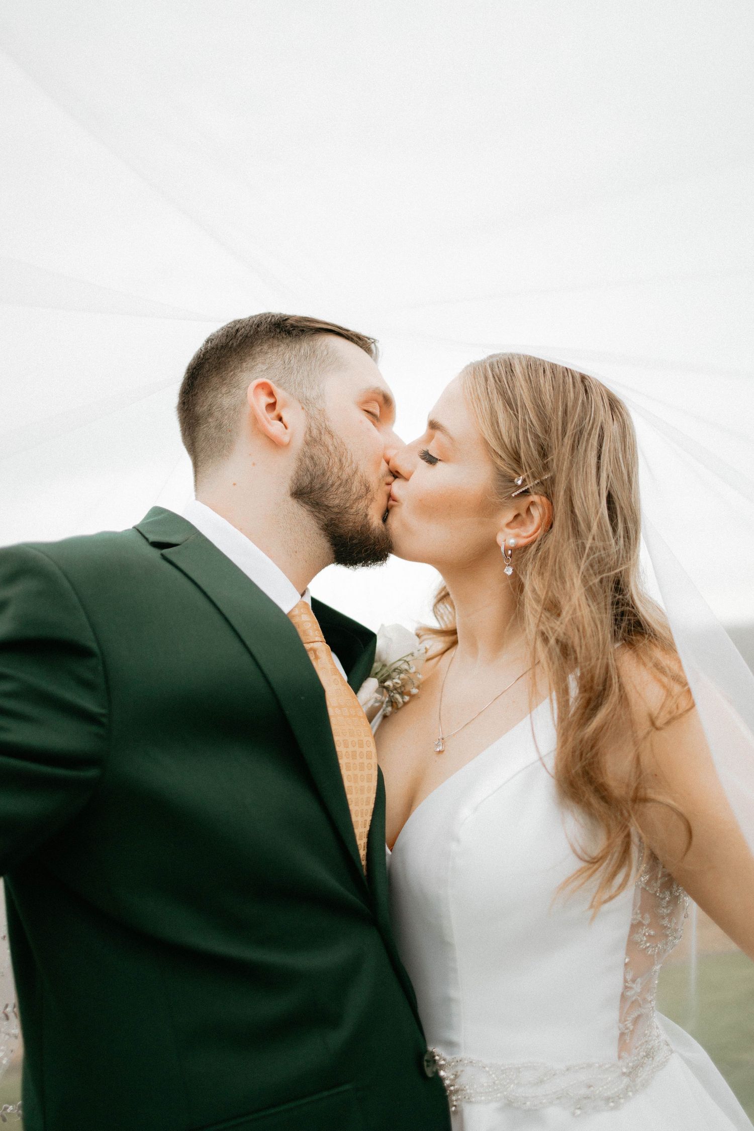 A romantic wedding photography series showing a couple kissing in formal attire against a light background.