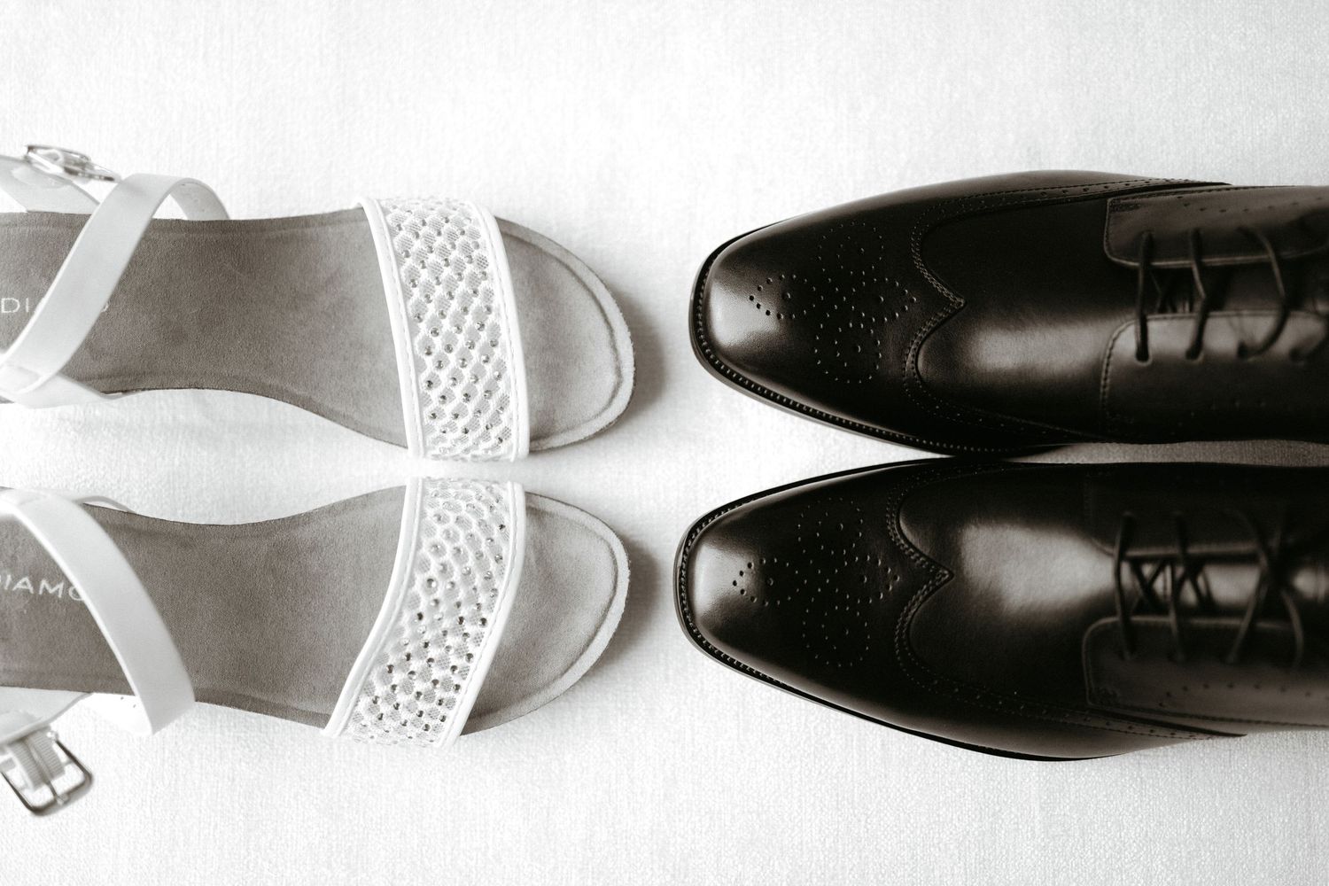 Black and white minimalist composition of formal dress shoes alternating with white sandals against a light background.