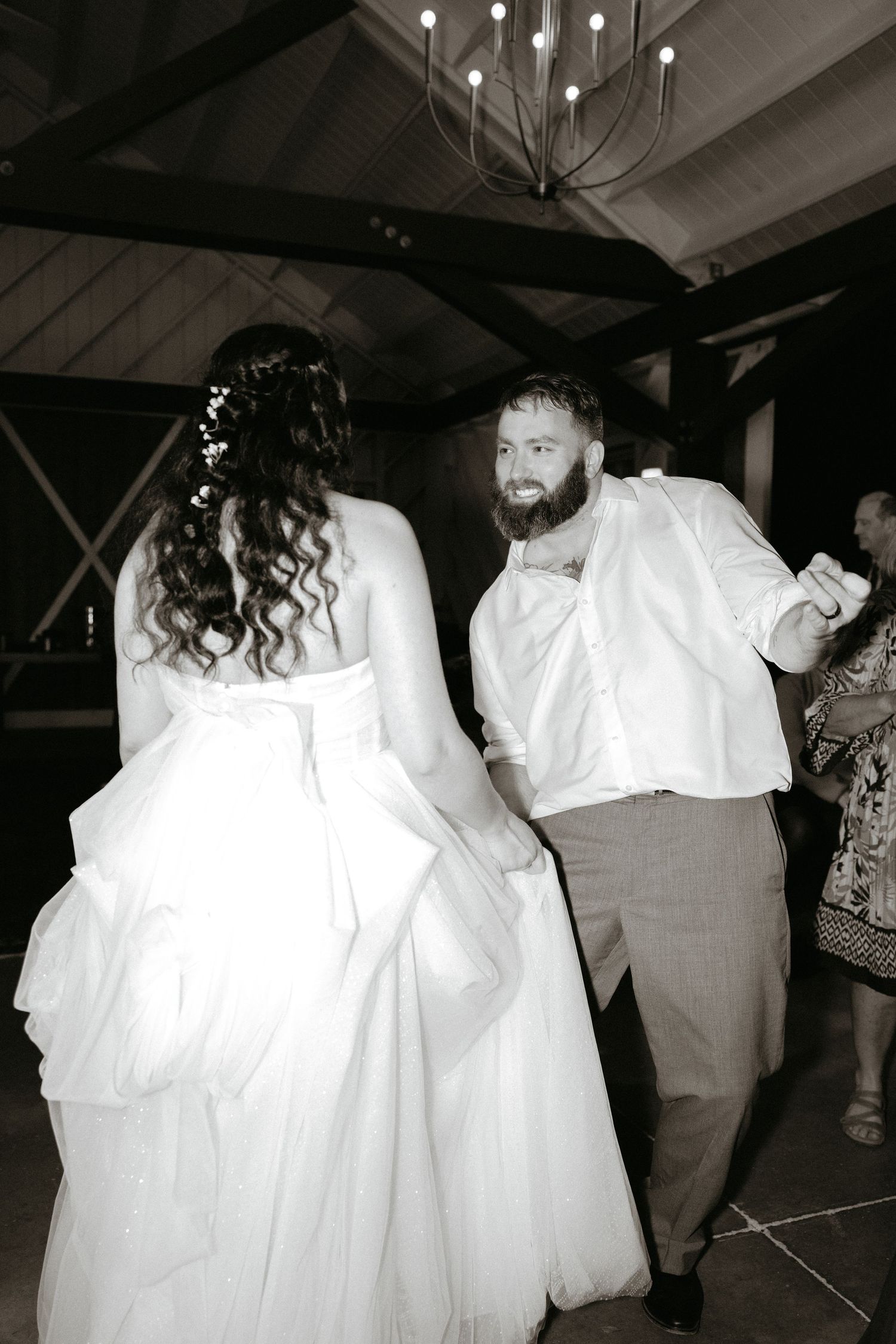 Multiple monochromatic shots of wedding guests dancing and celebrating on the dance floor.