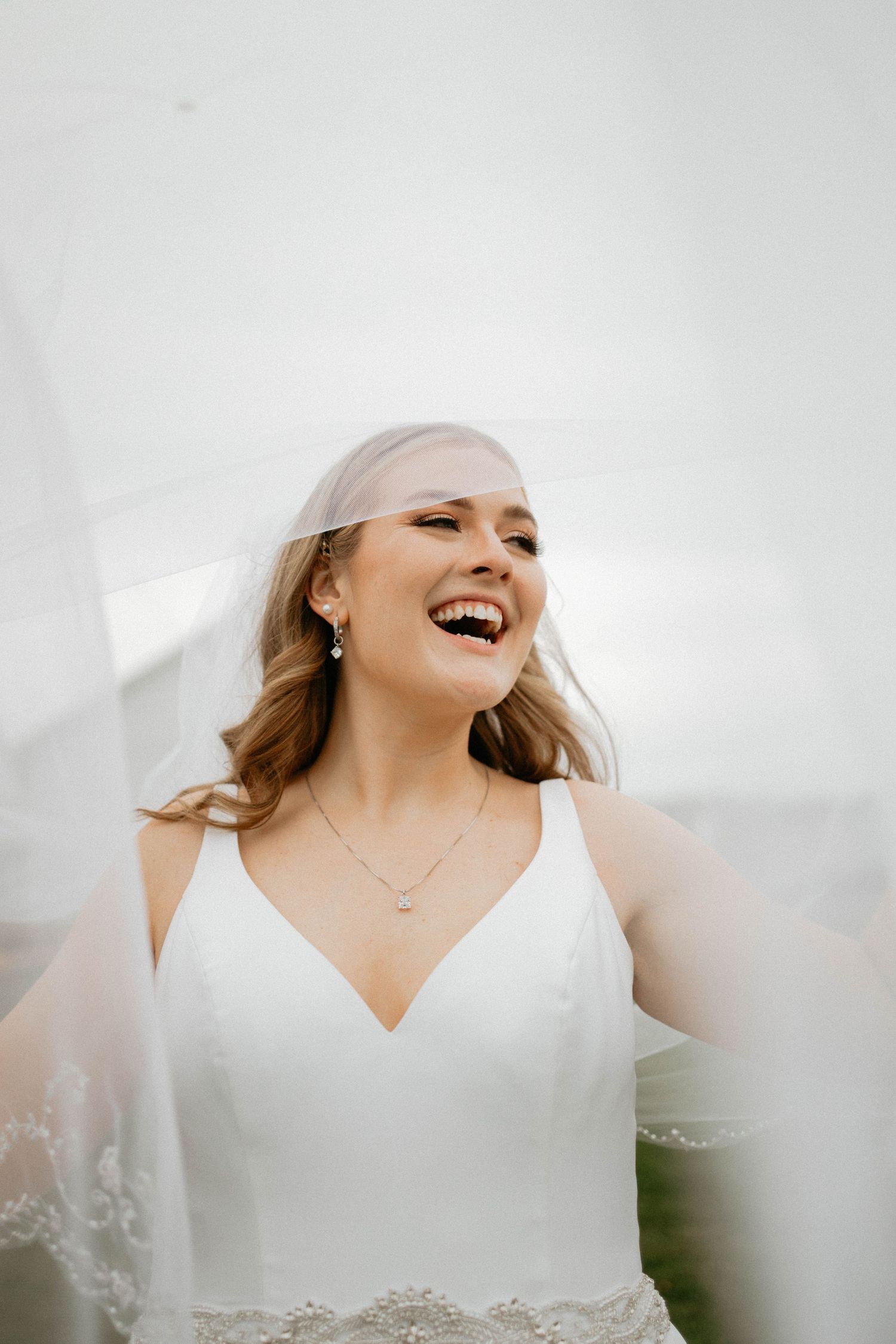 A joyful moment captured with a white wedding dress against a bright background.