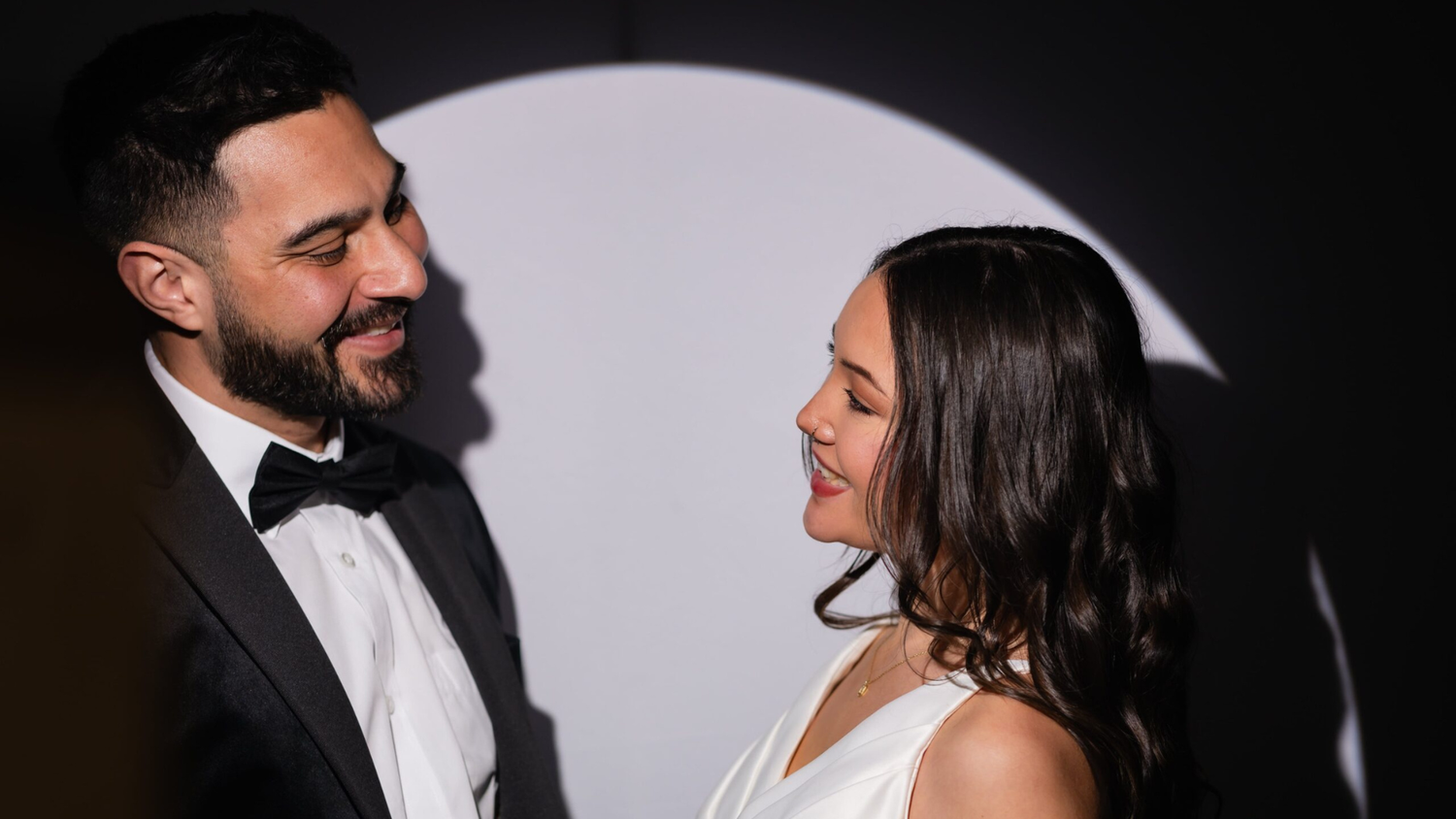 Two people in formal attire share an intimate moment and joyful laughter on their wedding day.