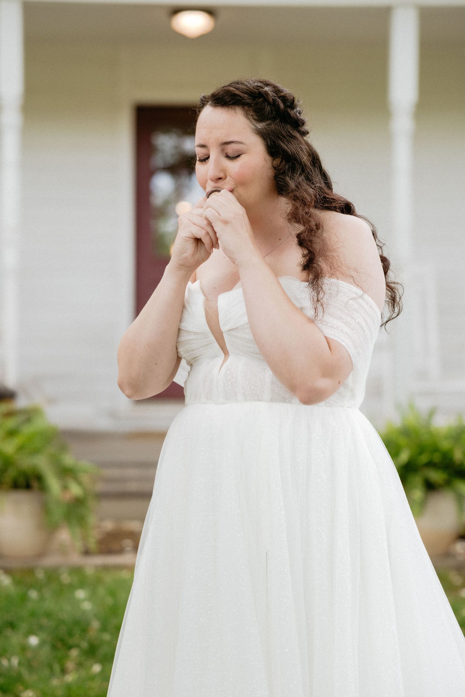 Someone in a flowing white dress standing outside a light-colored building.